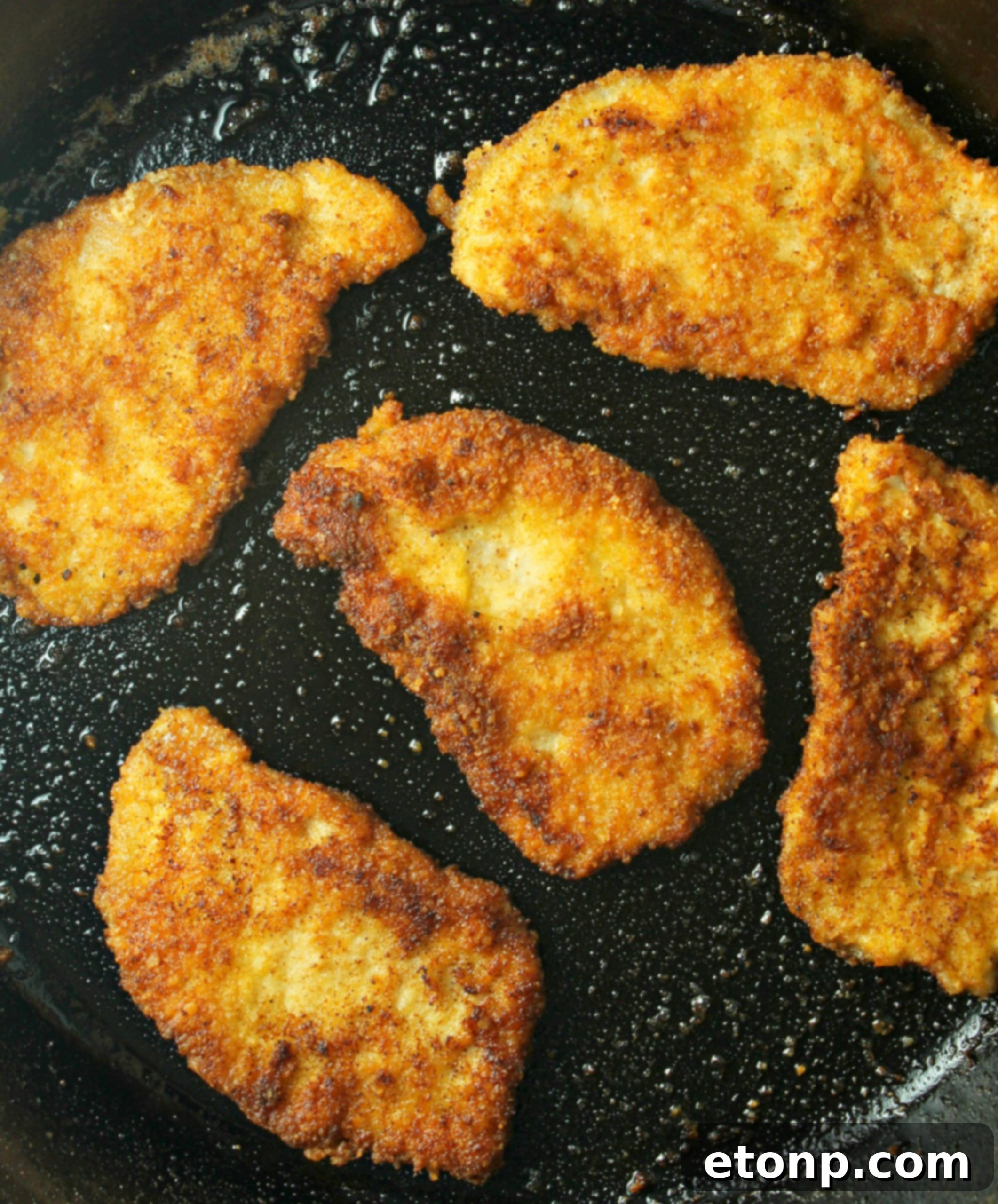 Pork Schnitzel frying in a hot skillet, achieving a golden-brown crust