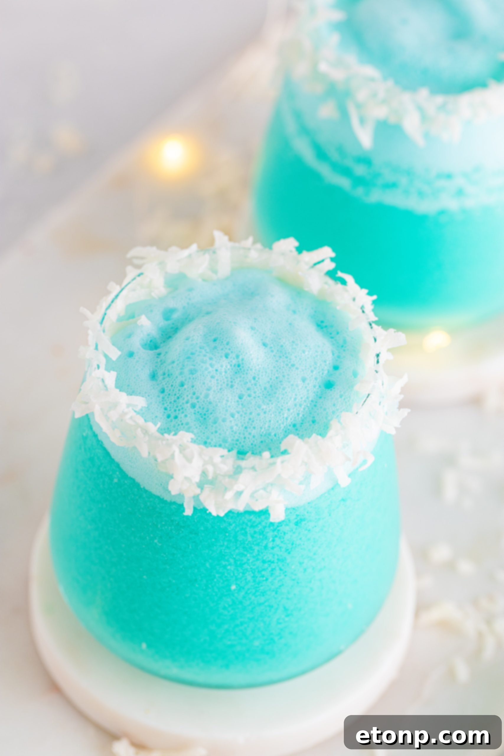A hand holding a Jack Frost Cocktail glass with a decorated rim