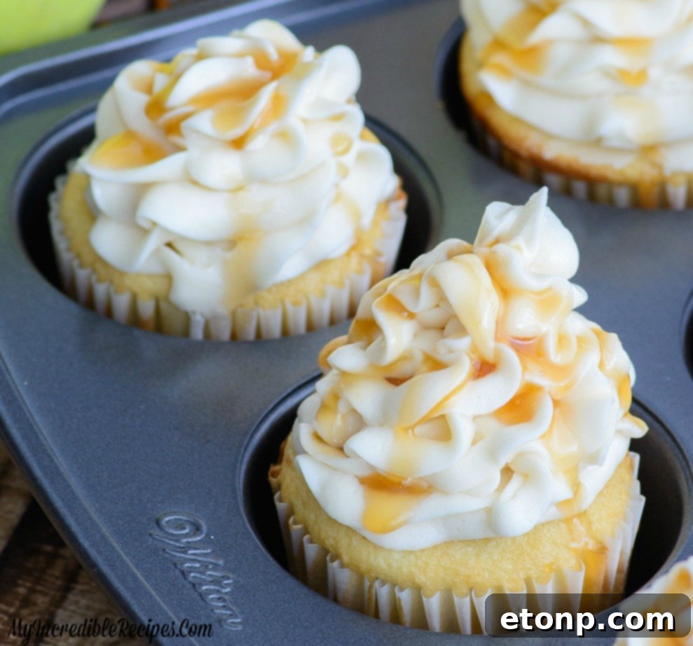 A plate of two frosted Caramel Apple Cupcakes with caramel drizzle