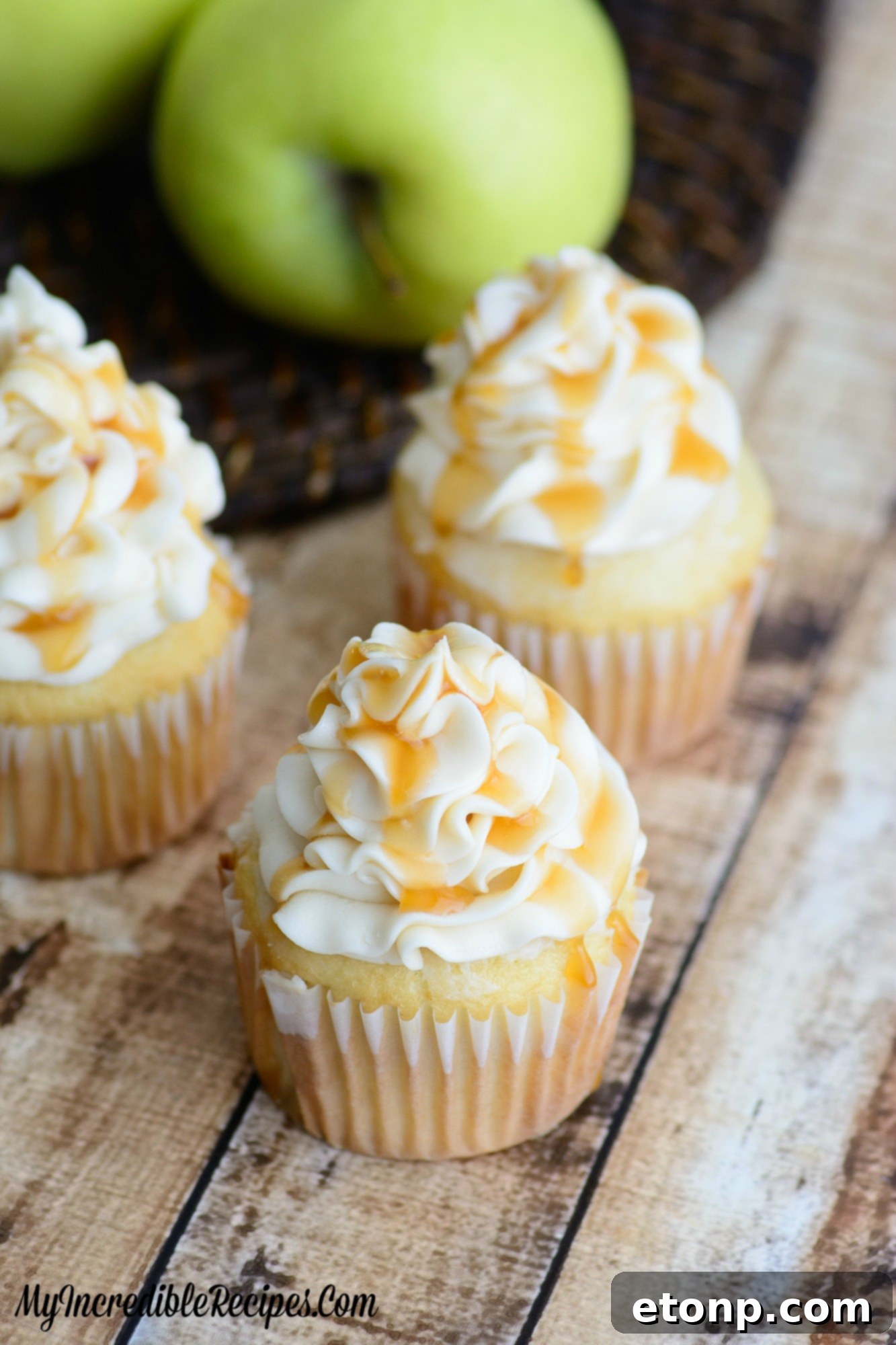 Seven frosted Caramel Apple Cupcakes on a rustic wooden surface