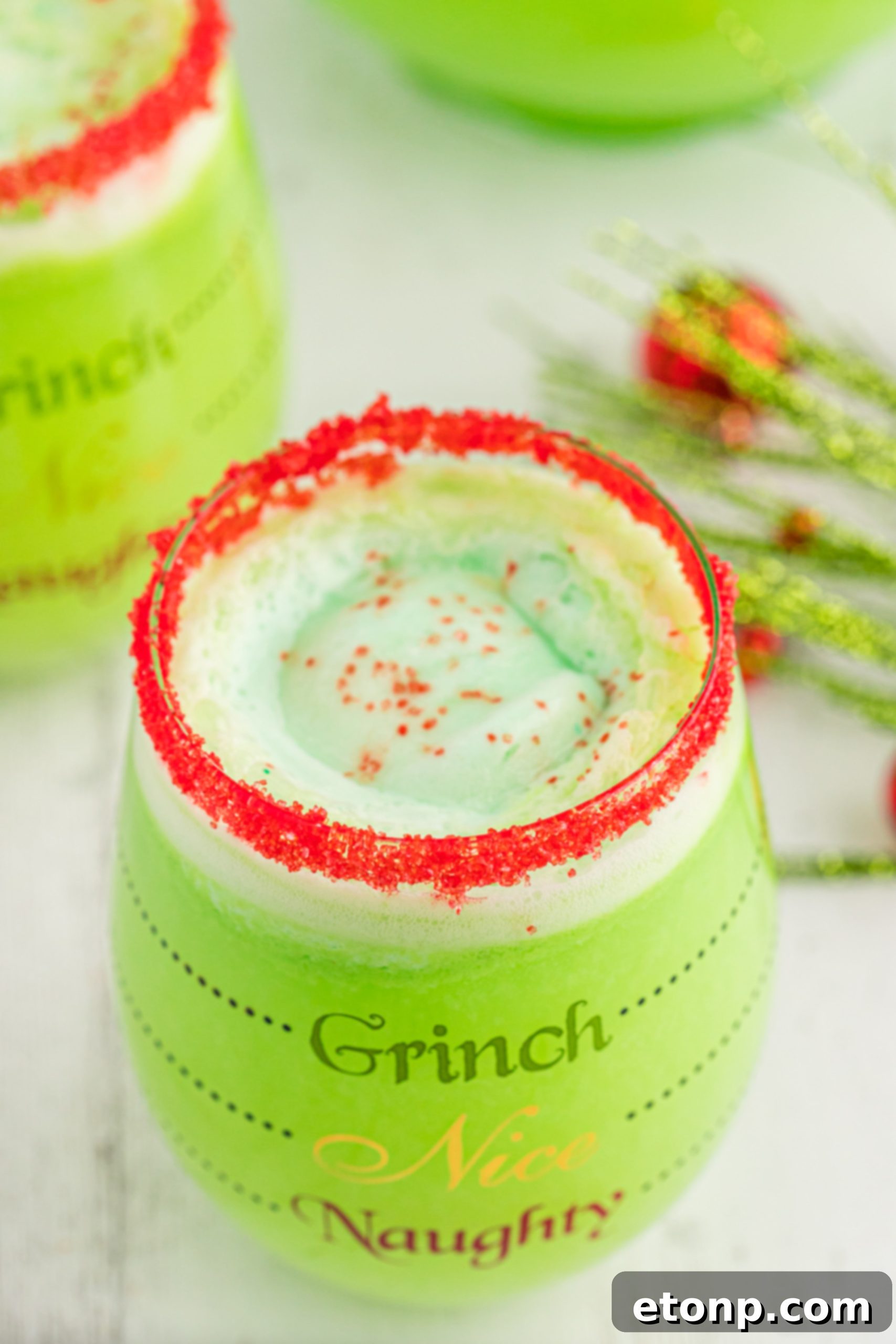 The Grinch's Heart-Growing Holiday Brew 3 Close-up of a glass rimmed with red sugar, prepared for Grinch Punch, showcasing its festive decoration.
