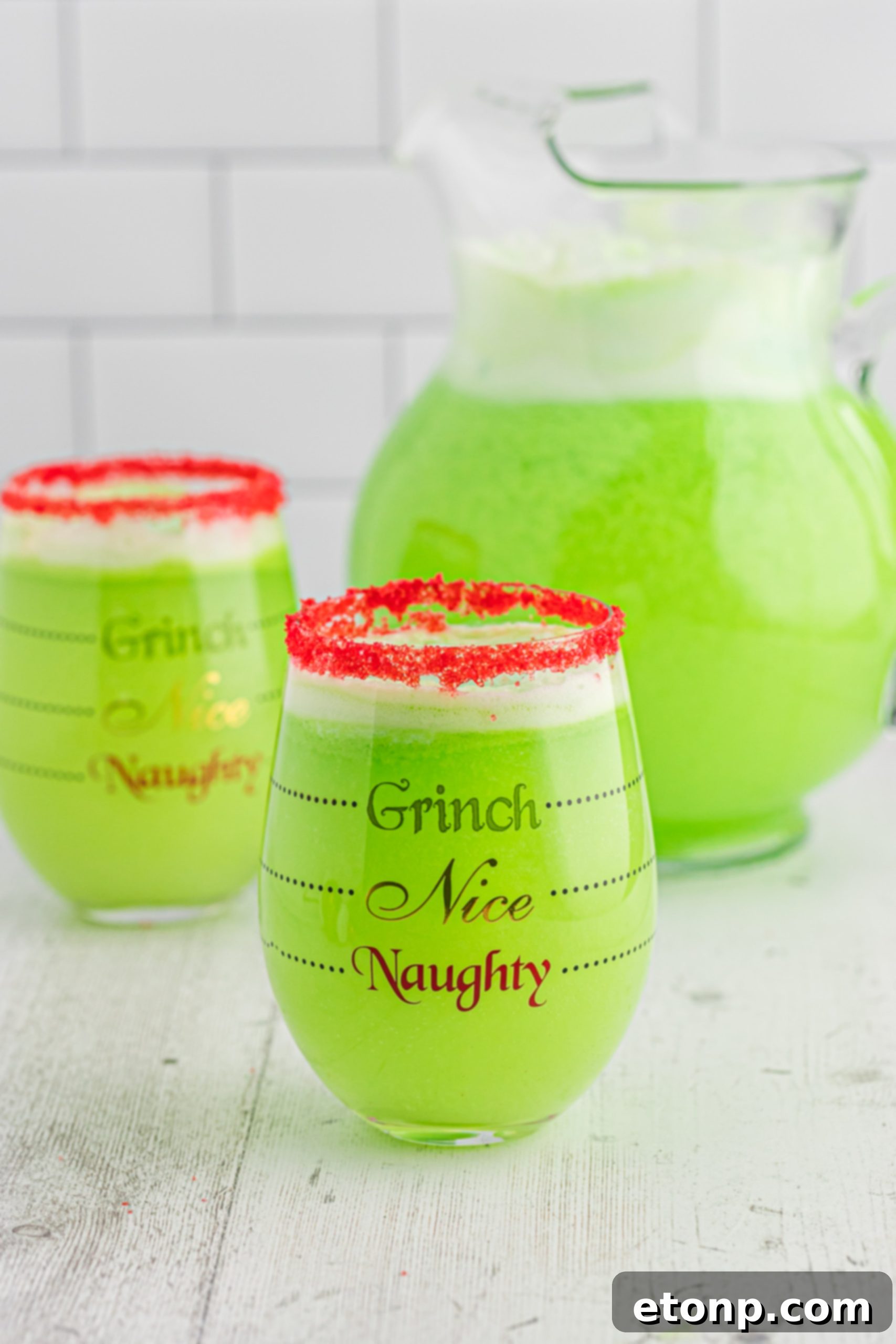 The Grinch's Heart-Growing Holiday Brew 5 Grinch Punch in a glass with a festive straw, showing the vibrant green color and frothy sherbet top.