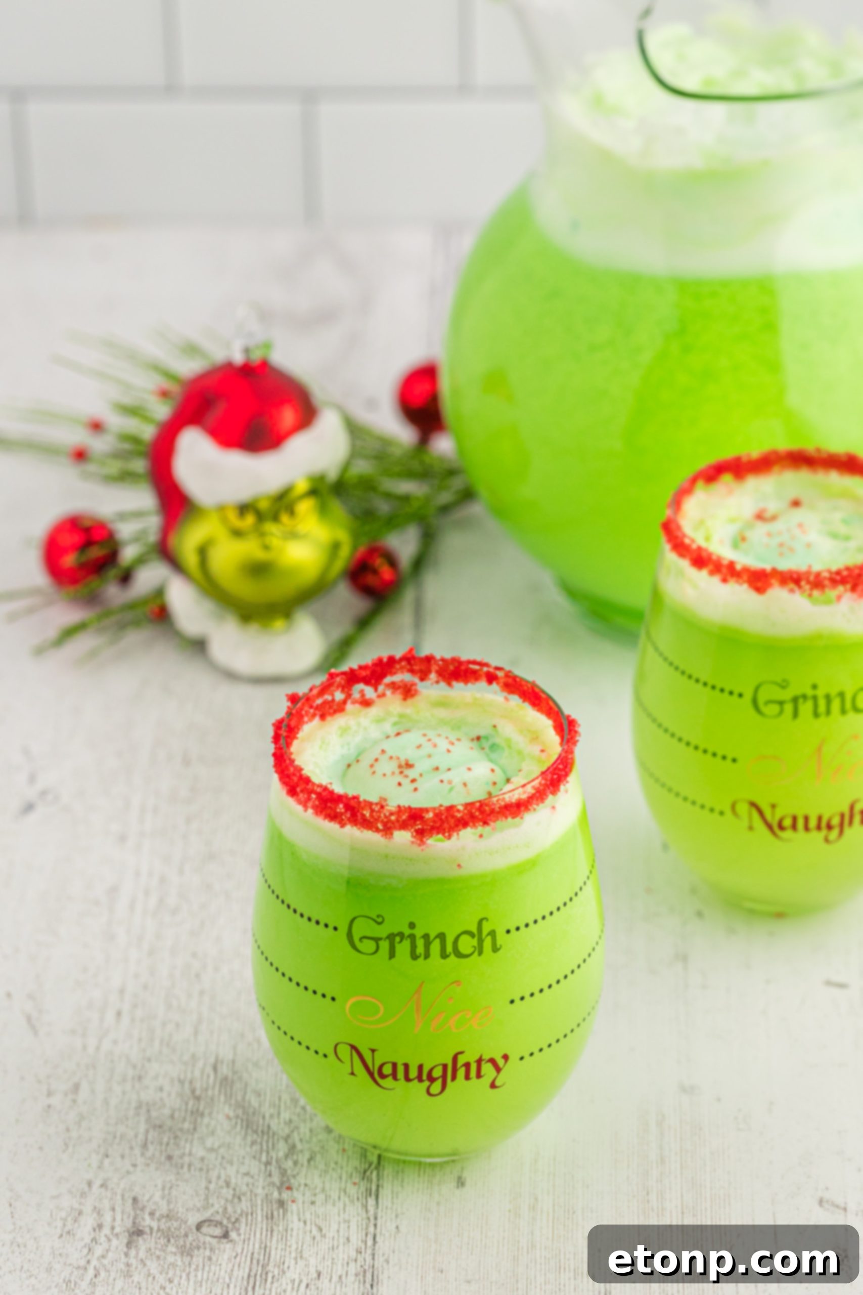 The Grinch's Heart-Growing Holiday Brew 9 Several glasses of Grinch Punch, some with green and red striped straws, on a wooden surface.