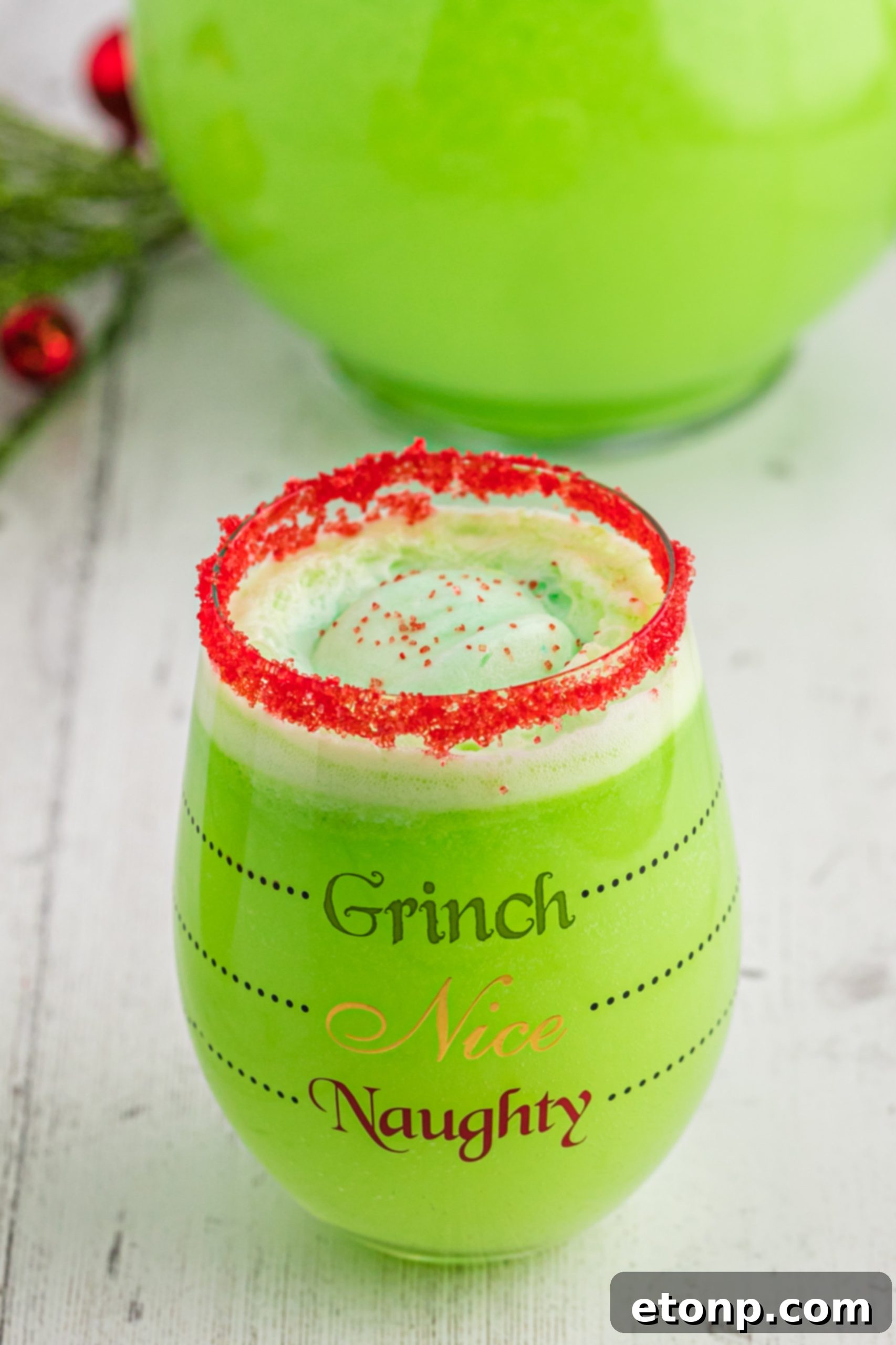 The Grinch's Heart-Growing Holiday Brew 10 Grinch Punch in a clear glass mug with a festive green and red straw, highlighting the drink's texture.