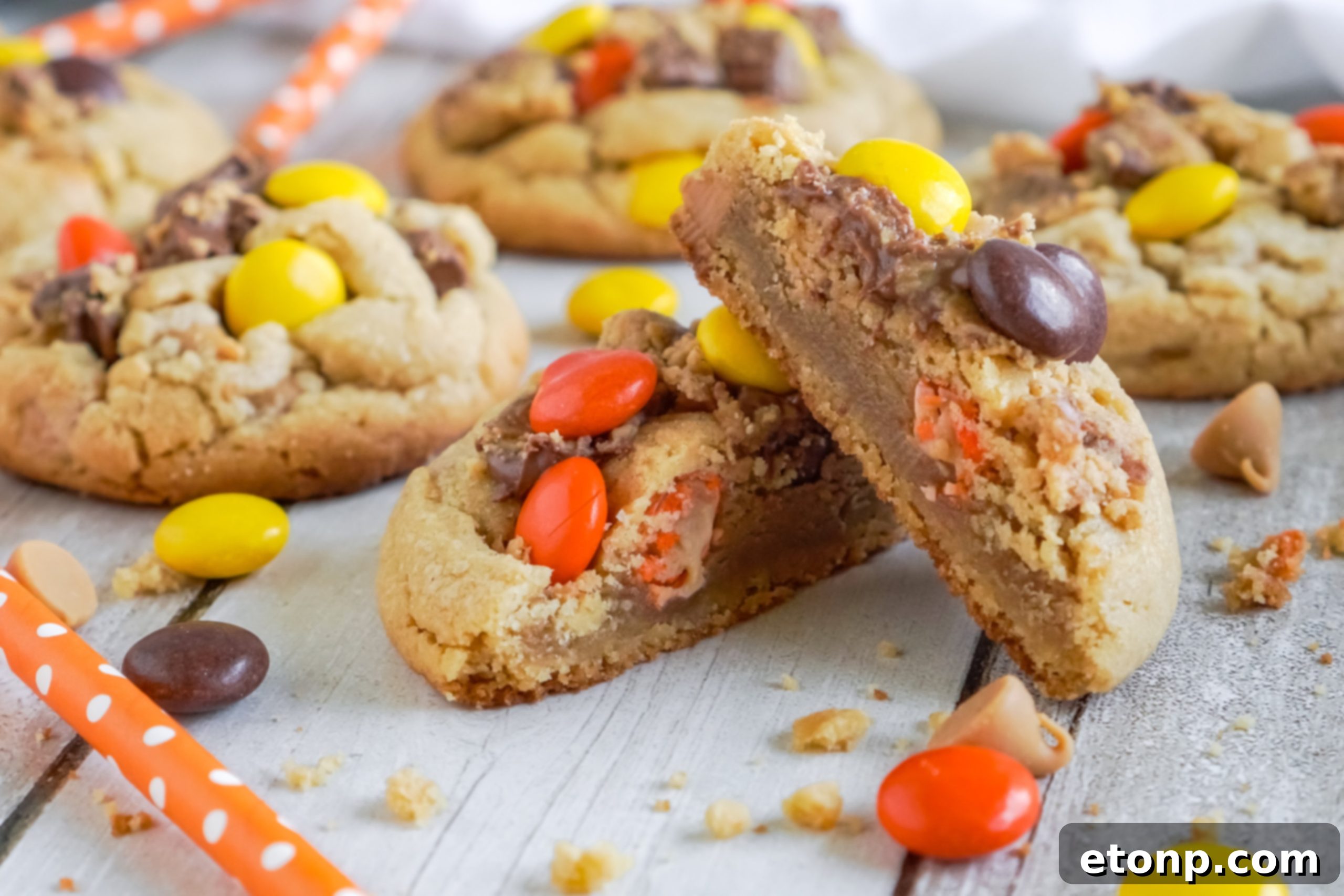 Hands placing Reese's candies onto warm, freshly baked cookies.