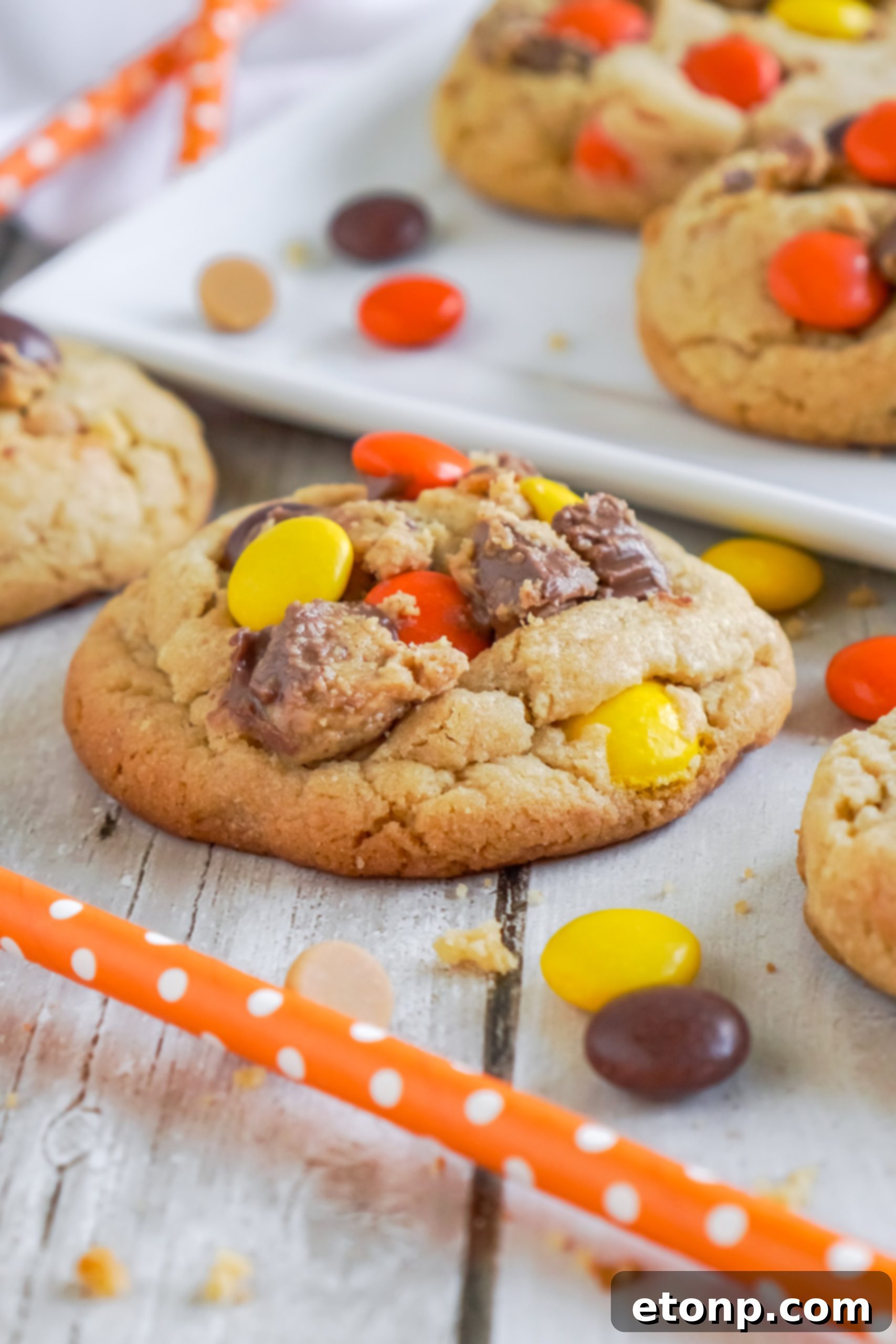 Several Reese's Peanut Butter Cup Cookies stacked neatly in a glass storage jar.