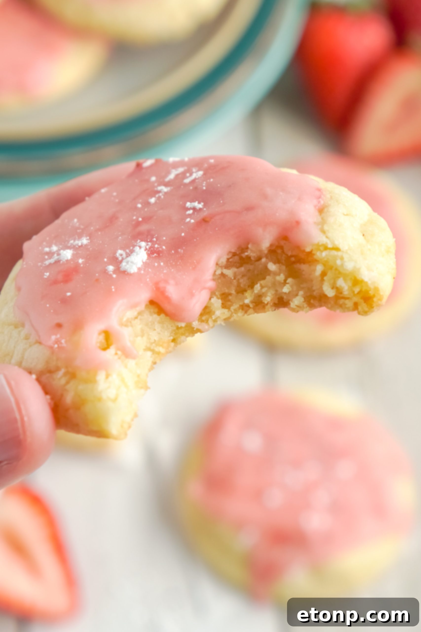 Hand drizzling strawberry glaze over a sugar cookie