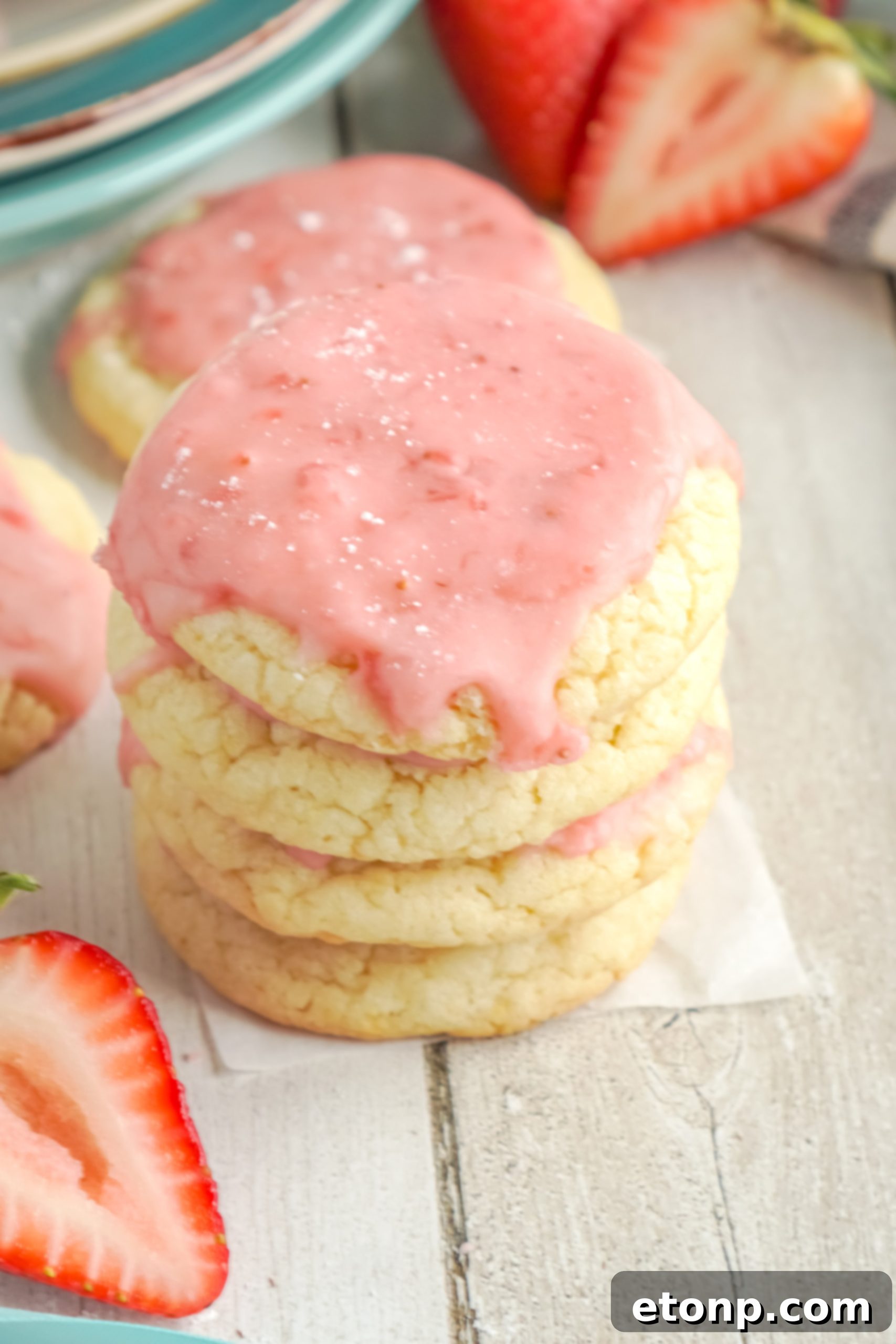 Two hands holding a strawberry glazed sugar cookie