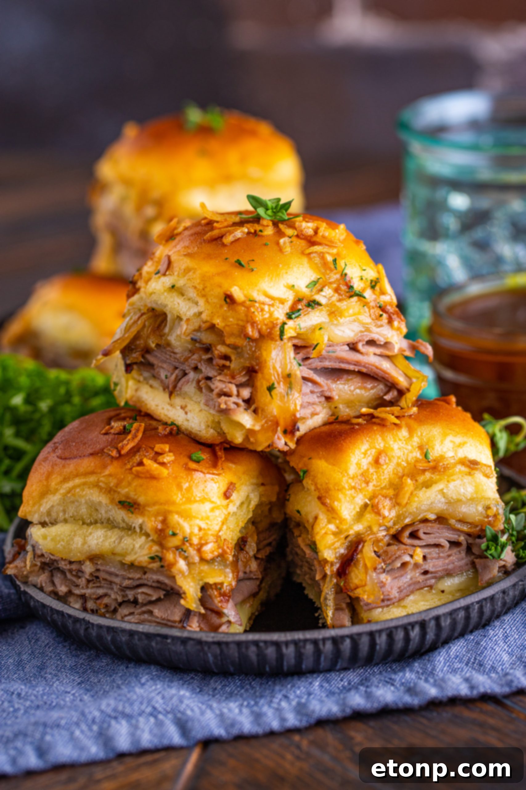 French Dip Sliders arranged on a black plate, showcasing their inviting golden-brown tops.
