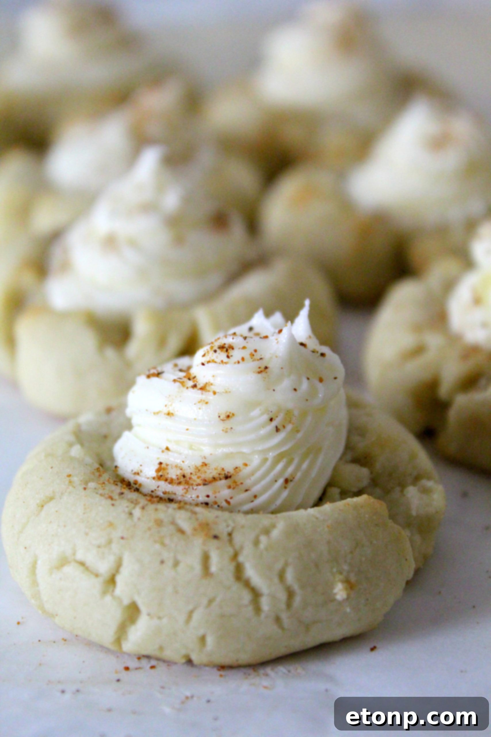 A plate of golden-brown, unfrosted Eggnog Thumbprint Cookies, showing their perfect shape and readiness for frosting, hinting at their delicious potential.