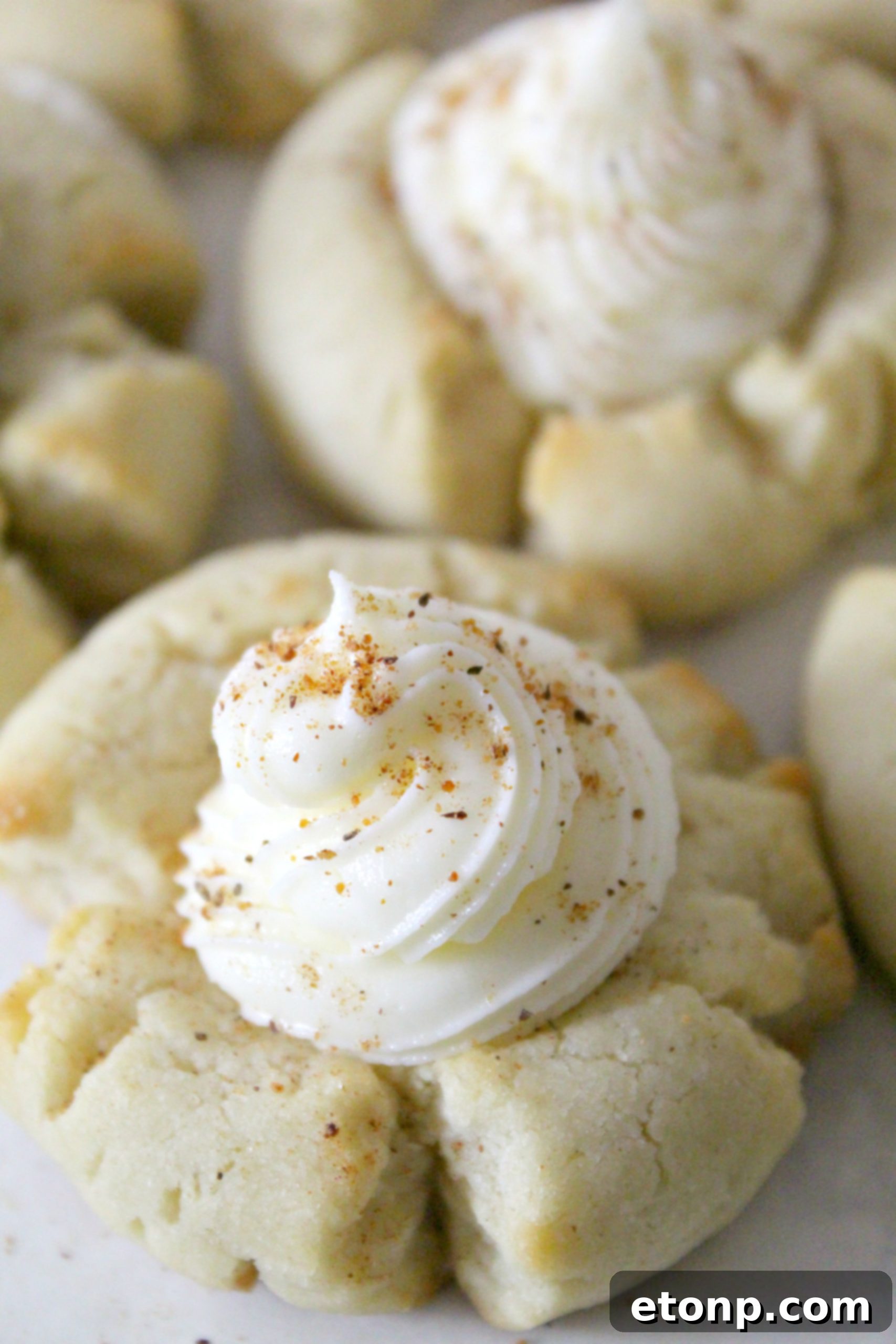 Freshly baked Eggnog Thumbprint Cookies, cooling on a wire rack against a soft, blurred background, showcasing their light golden hue and inviting texture.