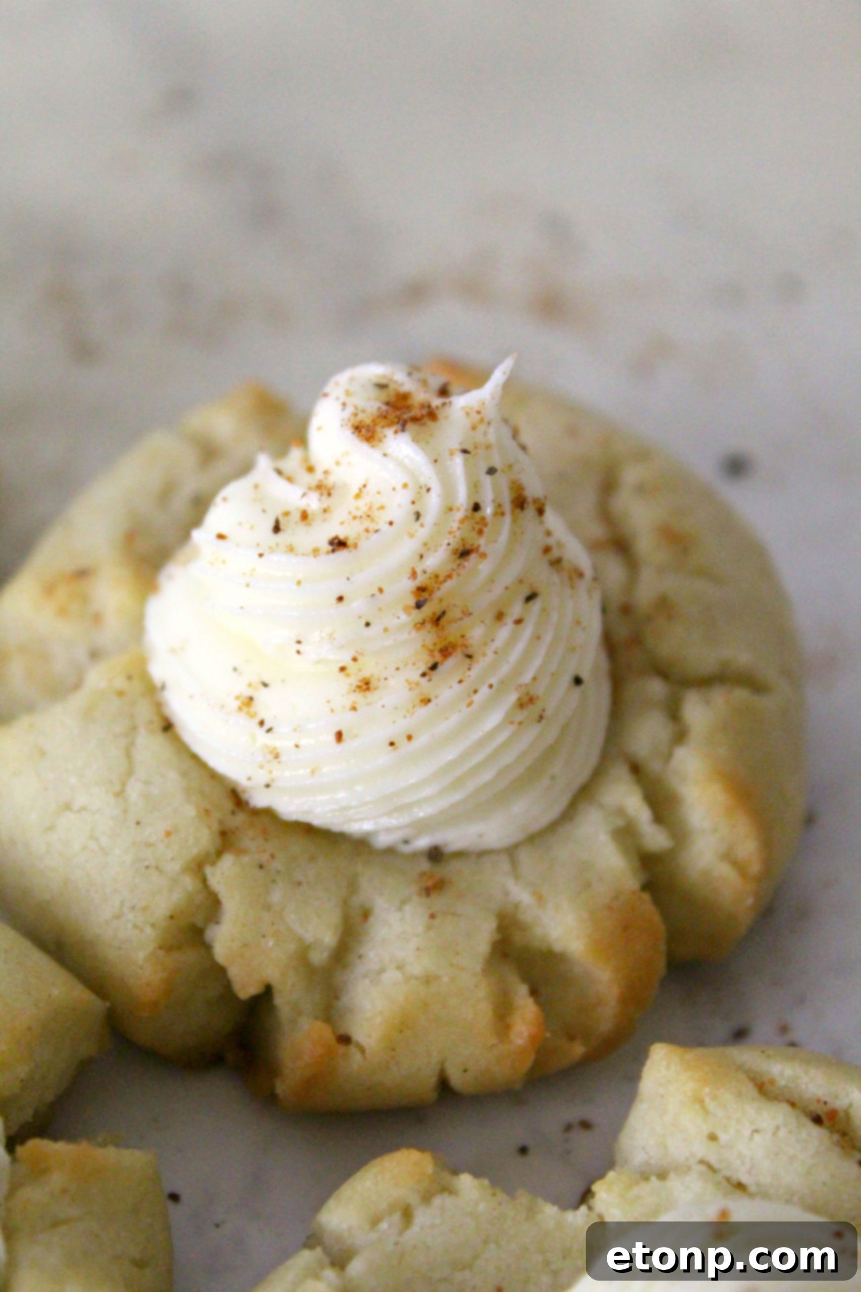 A close-up view of freshly baked, unfrosted Eggnog Thumbprint Cookies arranged on a baking sheet, golden and ready for their delicious rum buttercream topping.
