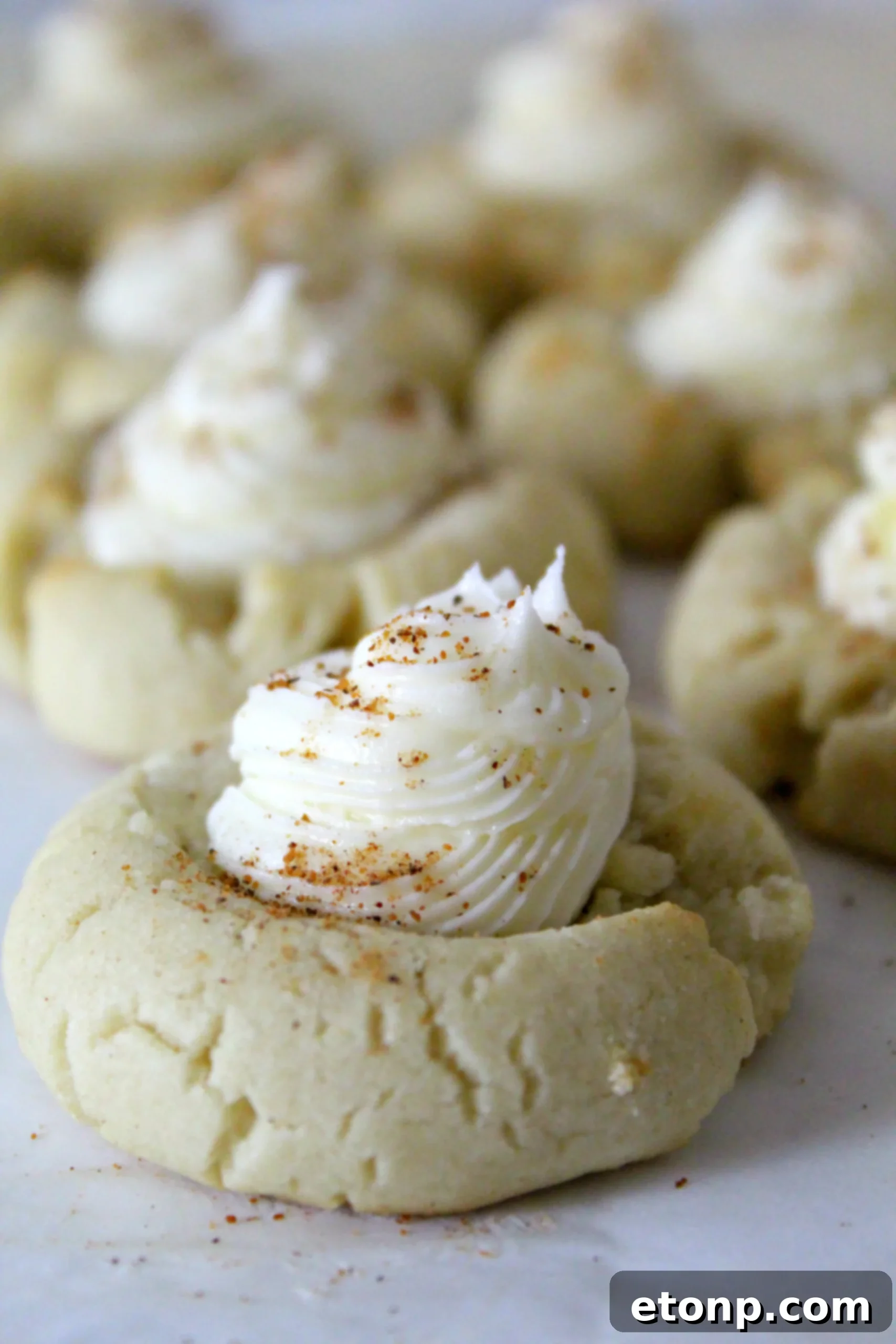 A festive arrangement of Eggnog Thumbprint Cookies, some frosted and some plain, showcasing their appeal for holiday entertaining and gifting.