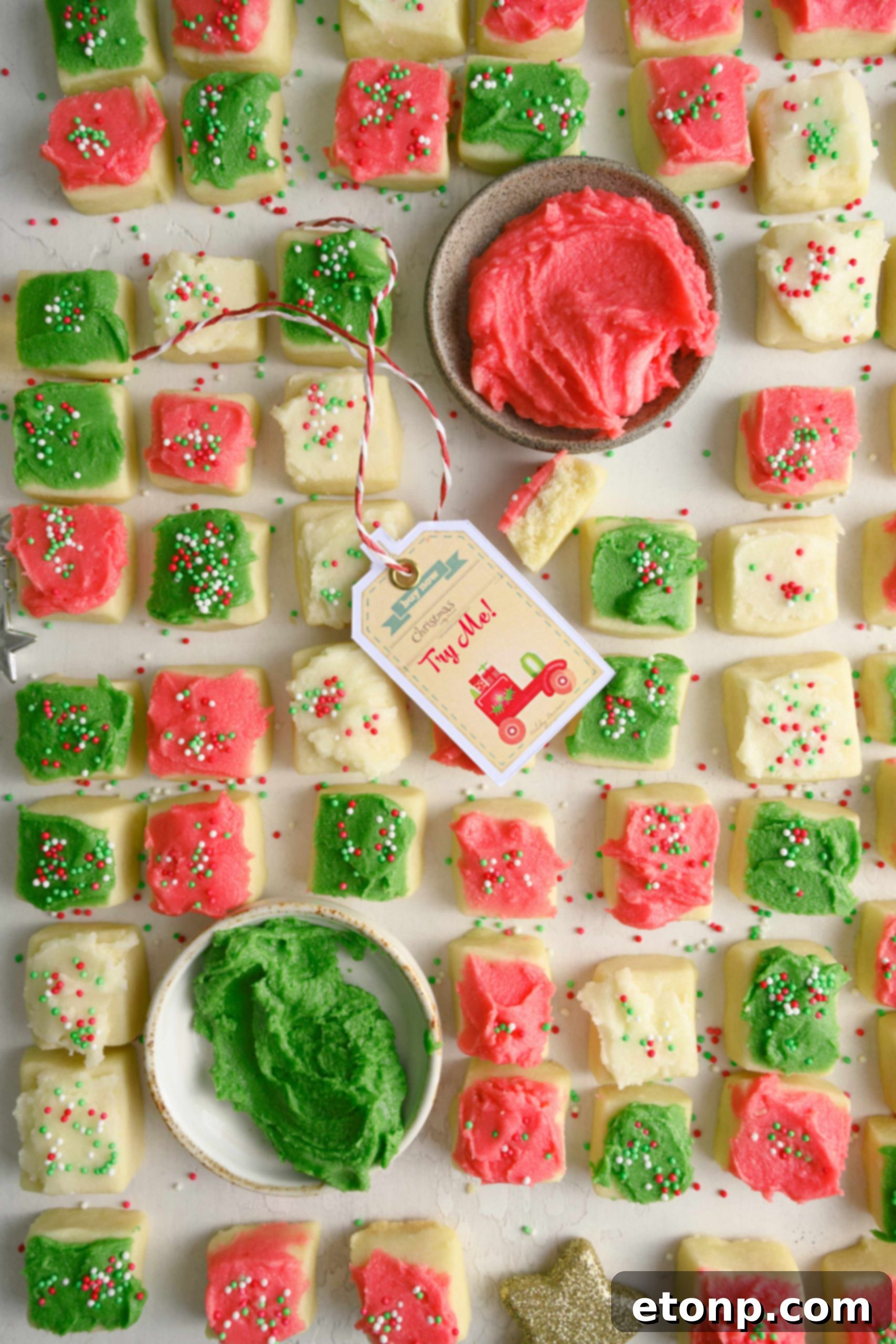 A close-up of a hand holding a single Christmas Sugar Cookie Bite, showcasing its delicate frosting and sprinkles.