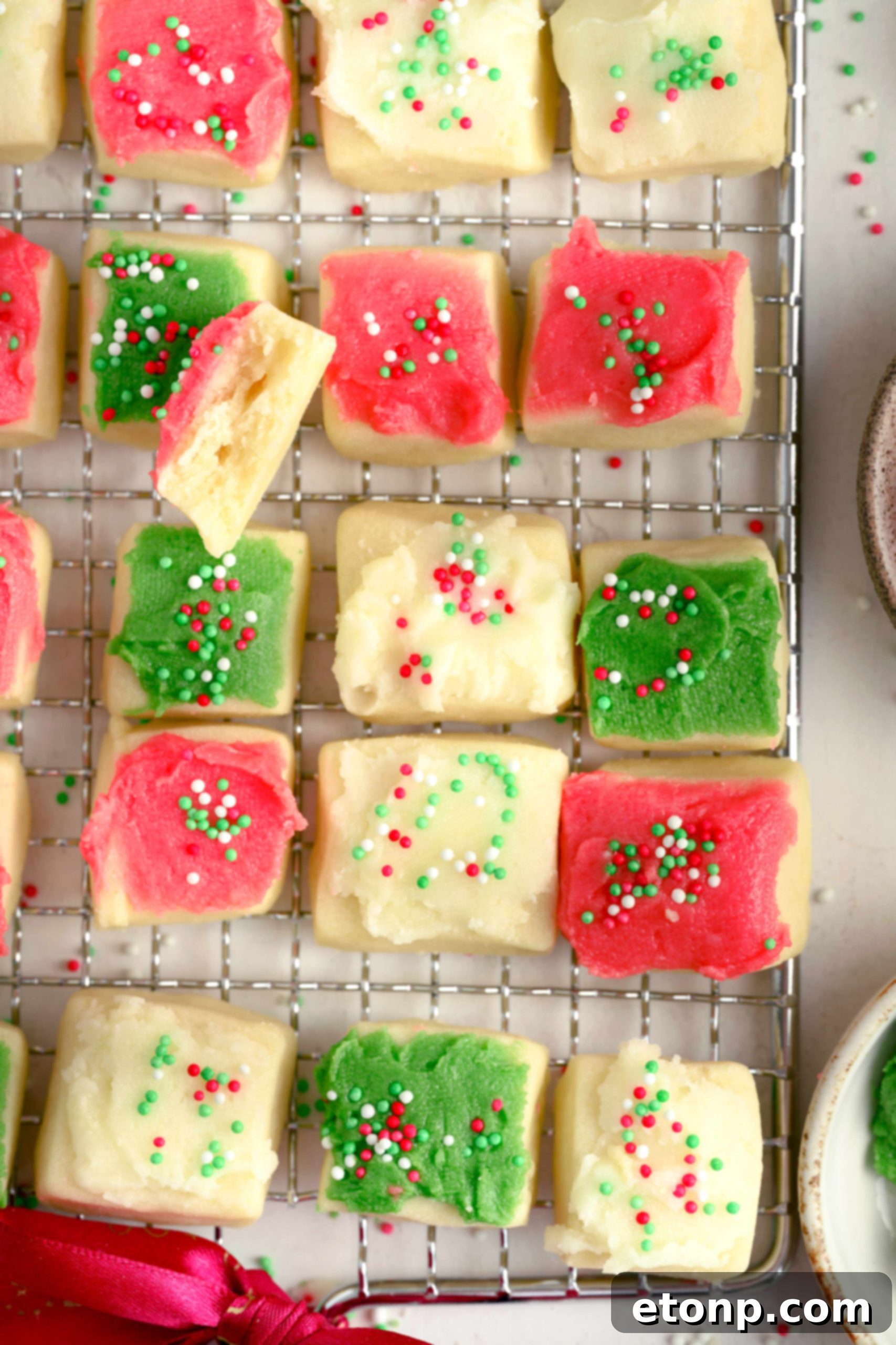 A collection of undecorated, freshly baked Christmas sugar cookie bites cooling on a wire rack.