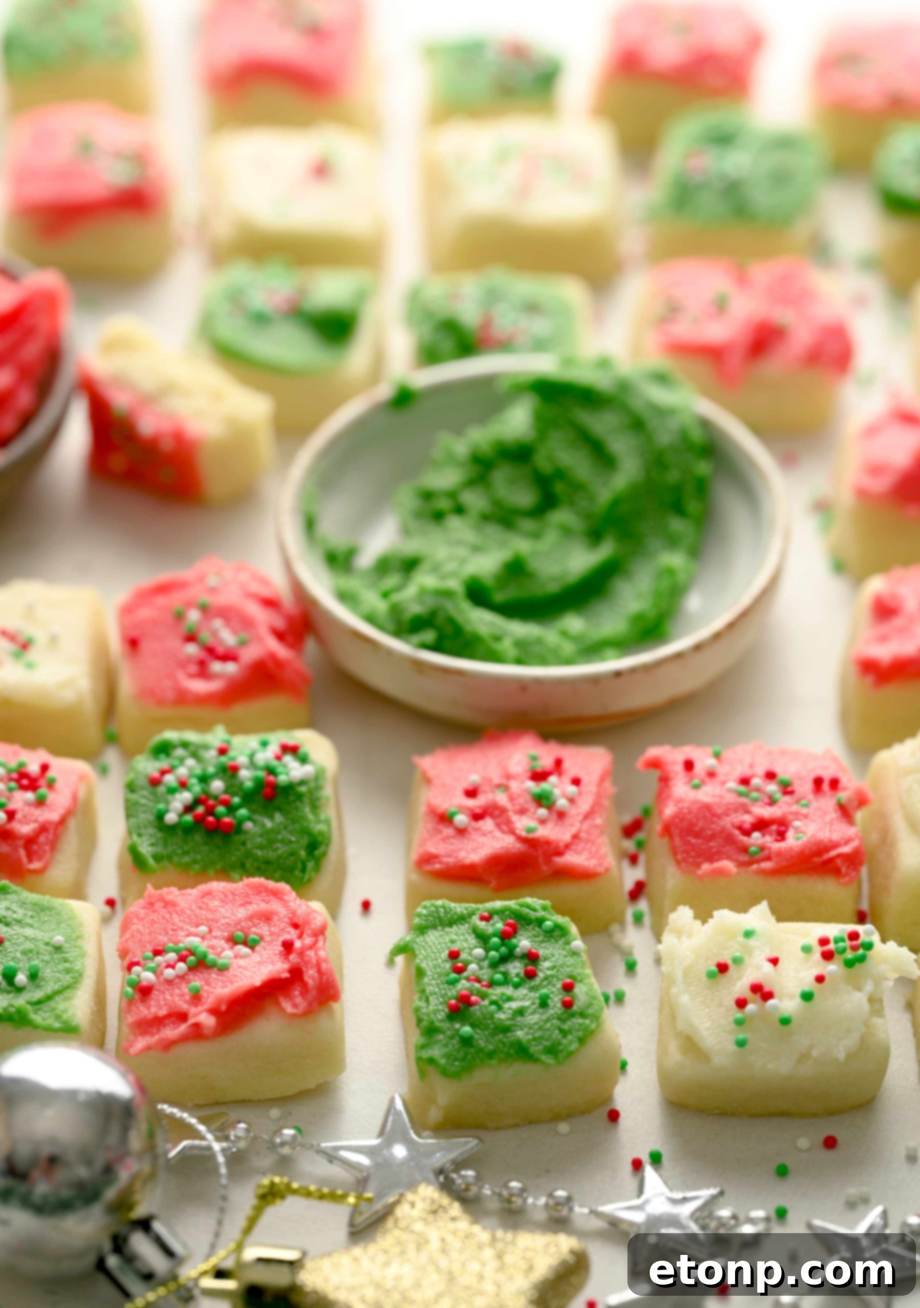 A close-up of Christmas Sugar Cookie Bites with green frosting, stacked neatly.
