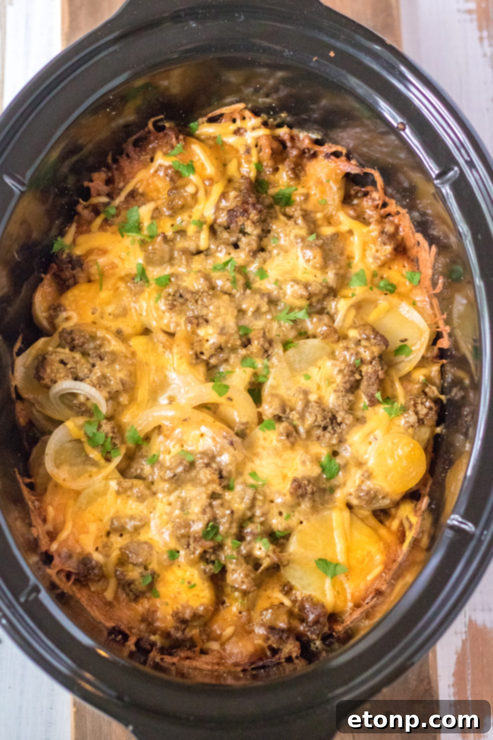 Overhead view of Slow Cooker Beef and Potato Au Gratin, showcasing the melted cheese and a hint of herbs.