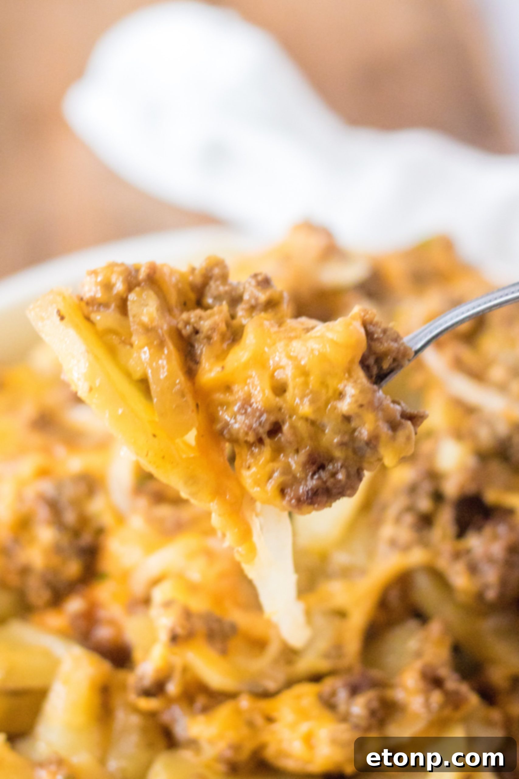 A large serving of Slow Cooker Beef and Potato Au Gratin scooped out, showing the layers and cheesy texture.