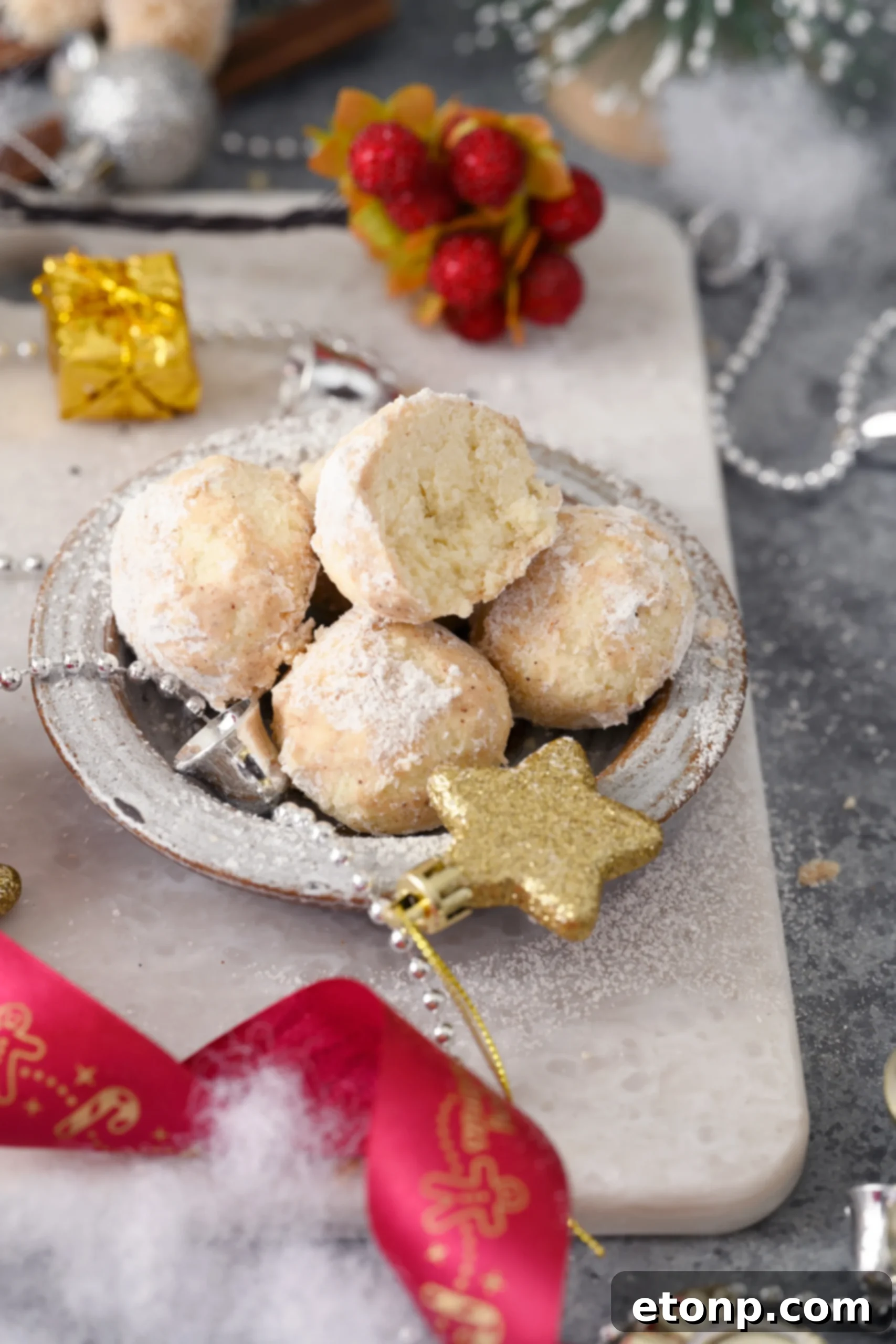 A festive arrangement of Cinnamon Mexican Wedding Cookies on a white serving platter, beautifully coated with a blend of powdered sugar and cinnamon, ready for a holiday gathering or special occasion.