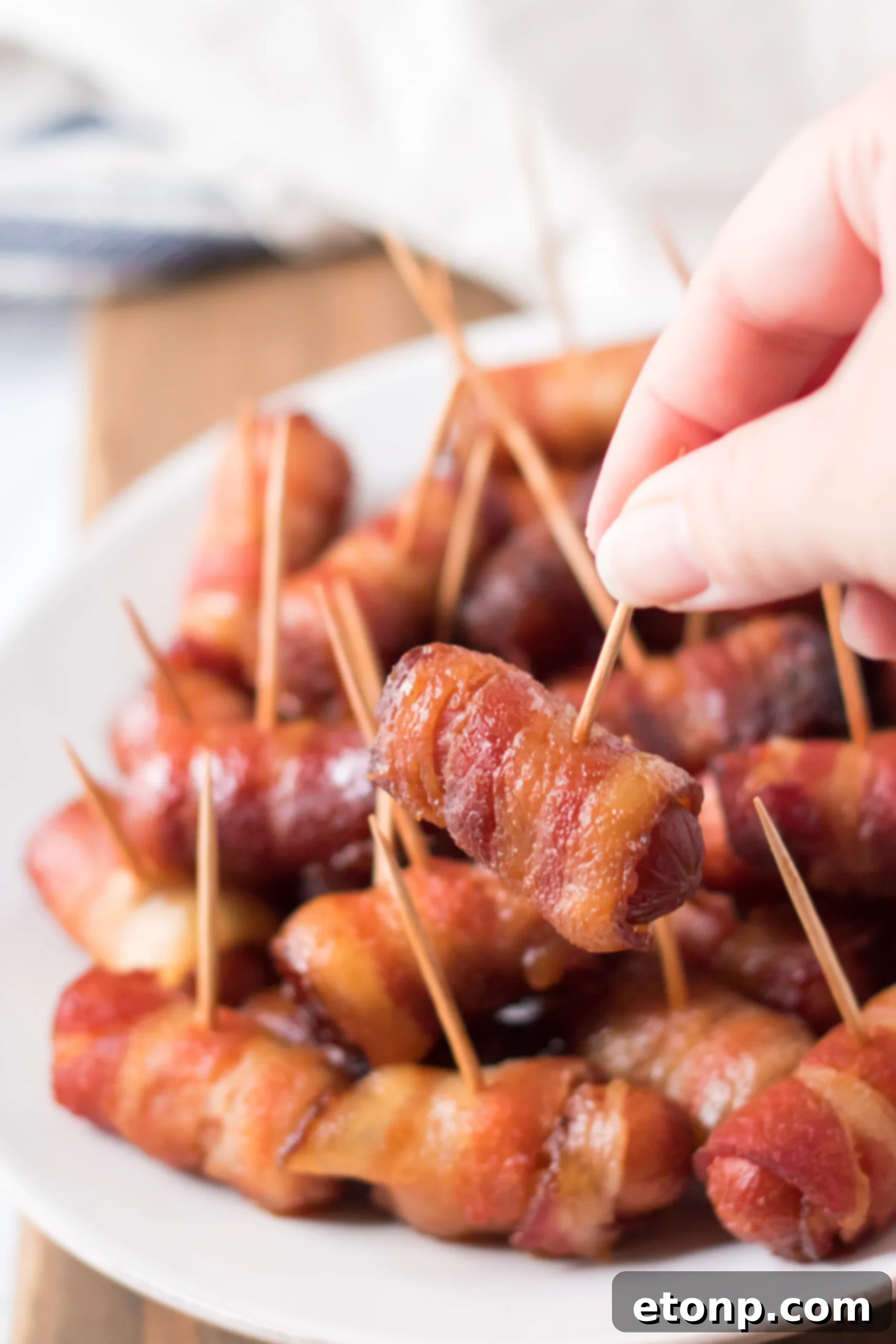 Crock-Pot Candy Bacon Smokies 7 Several Slow Cooker Bacon Wrapped Smokies on a platter, ready to be served.
