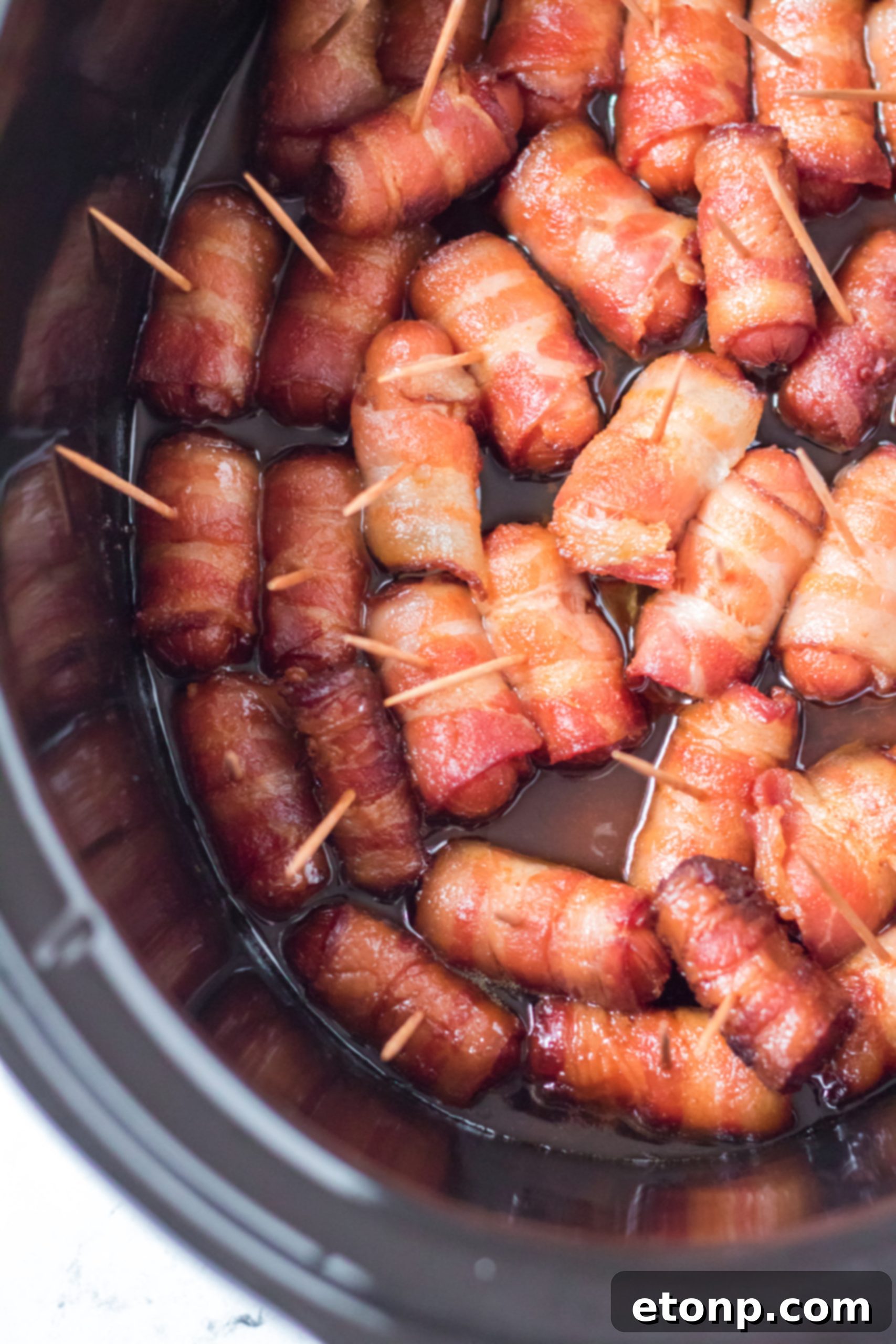 Crock-Pot Candy Bacon Smokies 9 Freshly prepared bacon-wrapped smokies arranged on a cutting board, ready for the slow cooker.