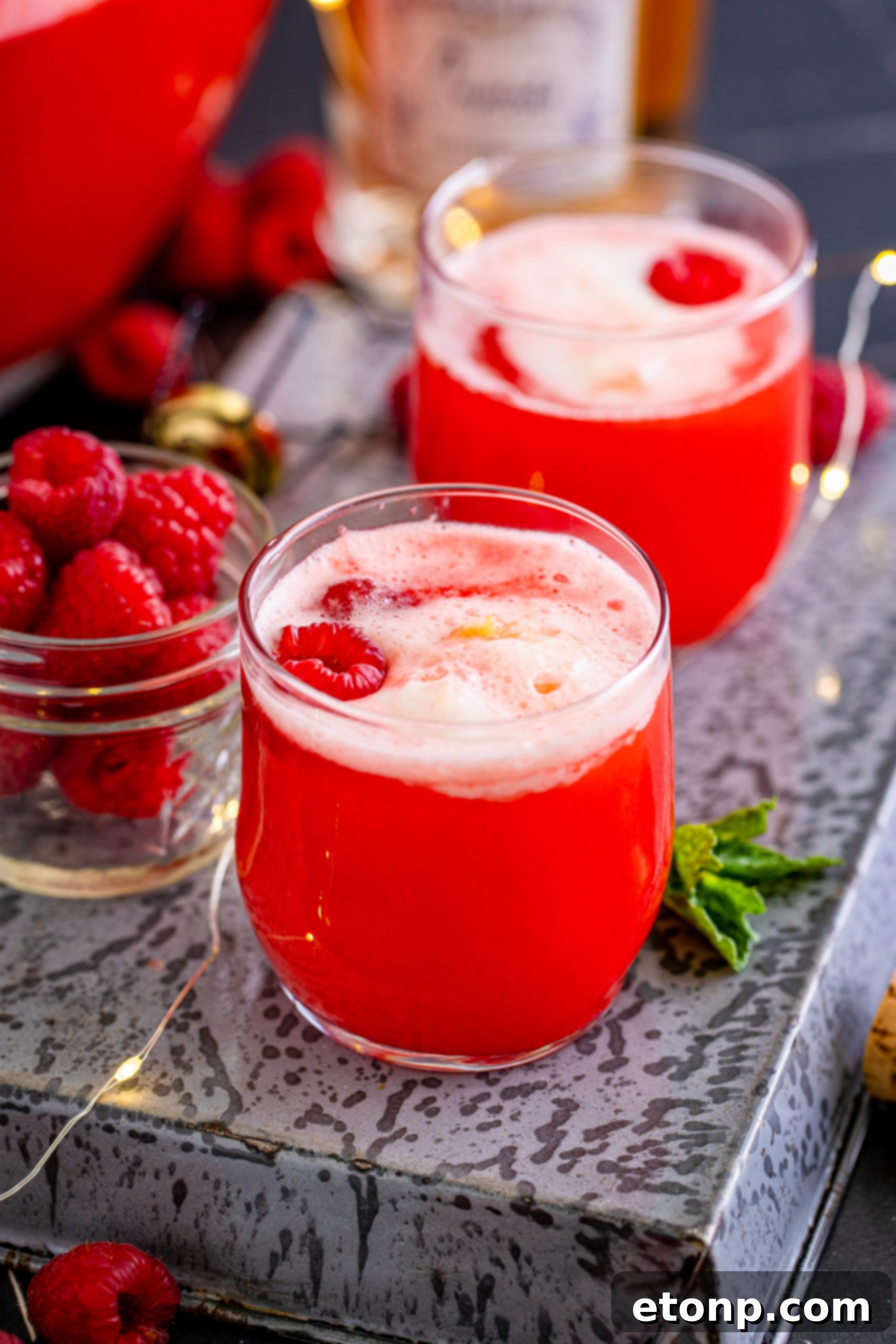 Close up of Boozy Sherbet Punch in a glass with pineapple and raspberry garnish