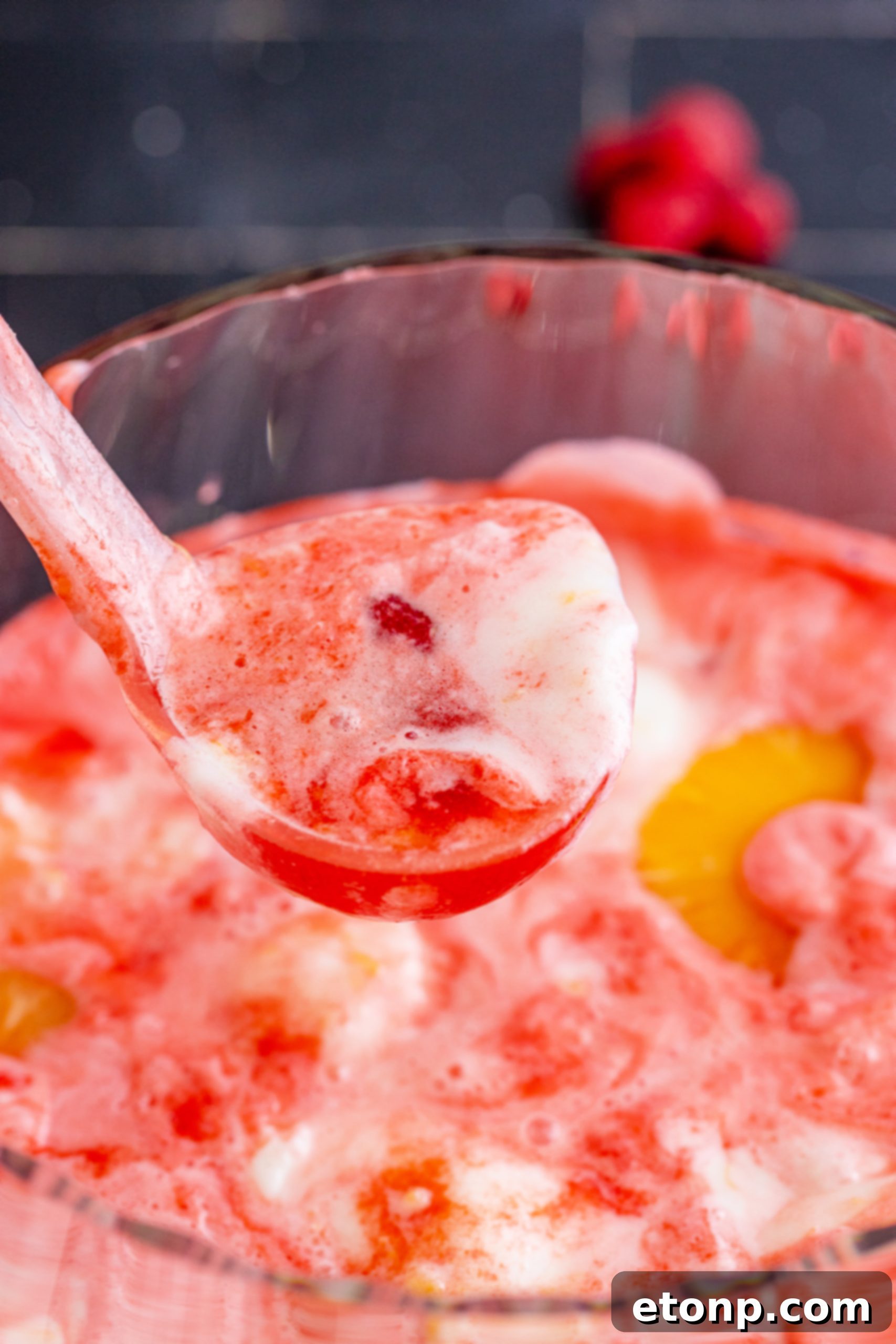 Boozy Sherbet Punch in a large glass bowl with scoops of sherbet and fruit slices