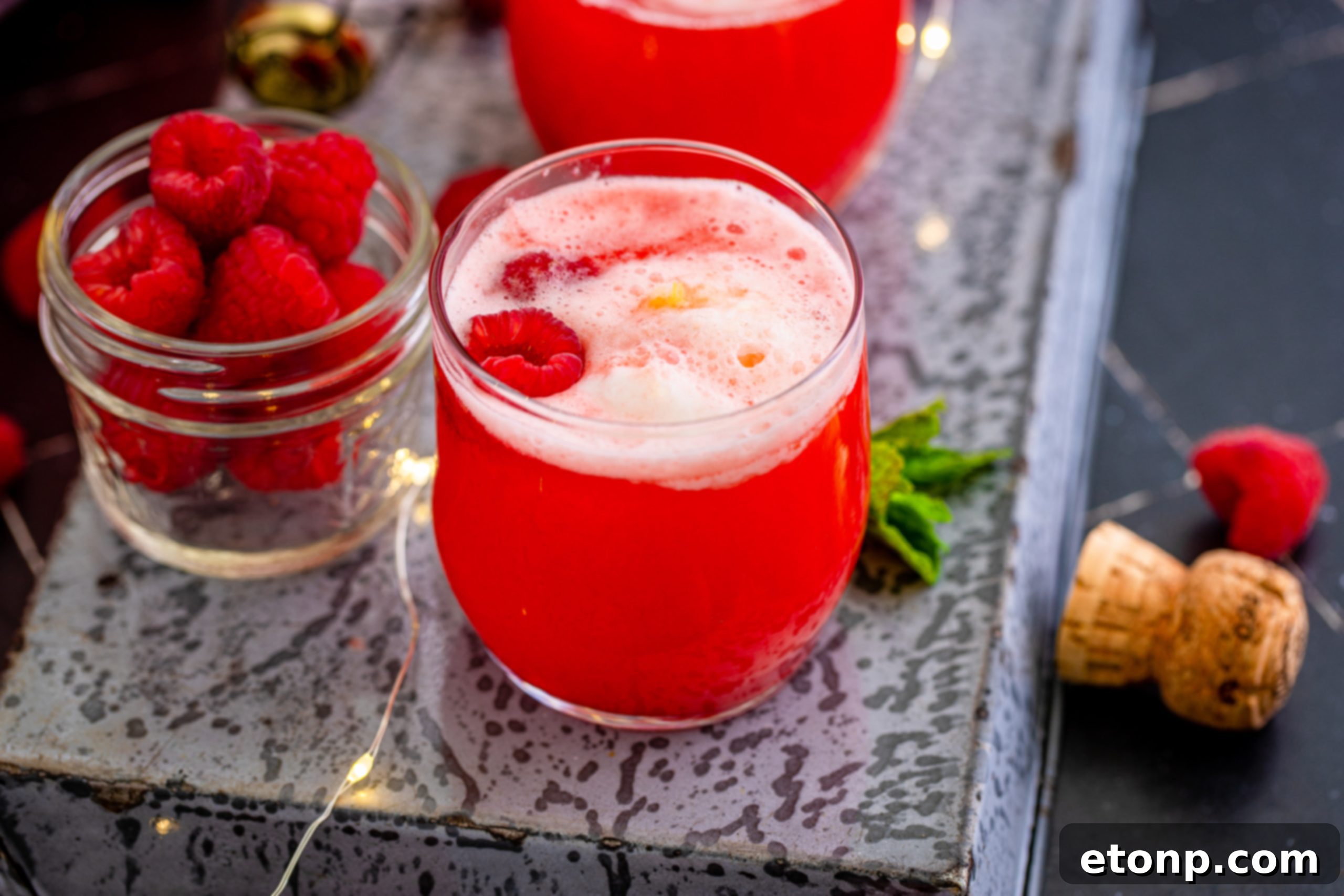 A bowl of Boozy Sherbet Punch with various garnishes and serving glasses