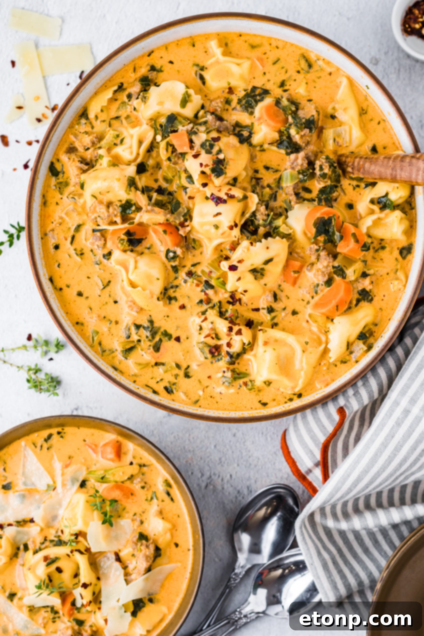 A bowl of slow cooker creamy tortellini soup with a spoon, showing the hearty texture and rich broth.