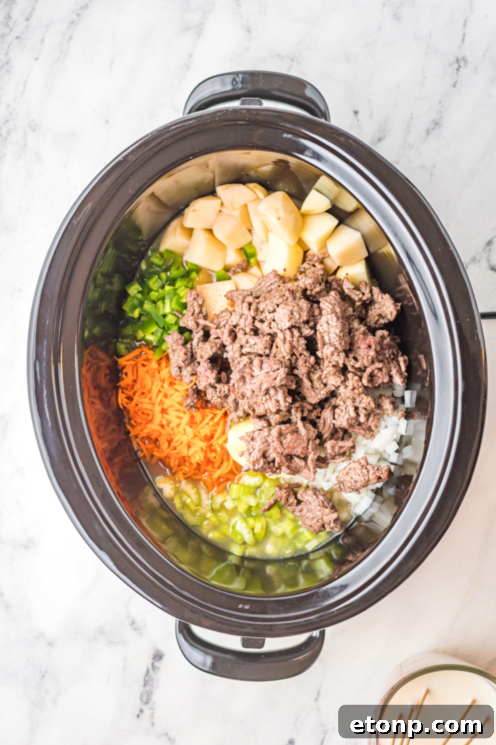 Close-up of slow cooker cheeseburger soup, highlighting the ground beef, diced potatoes, and melted cheese in a creamy base.