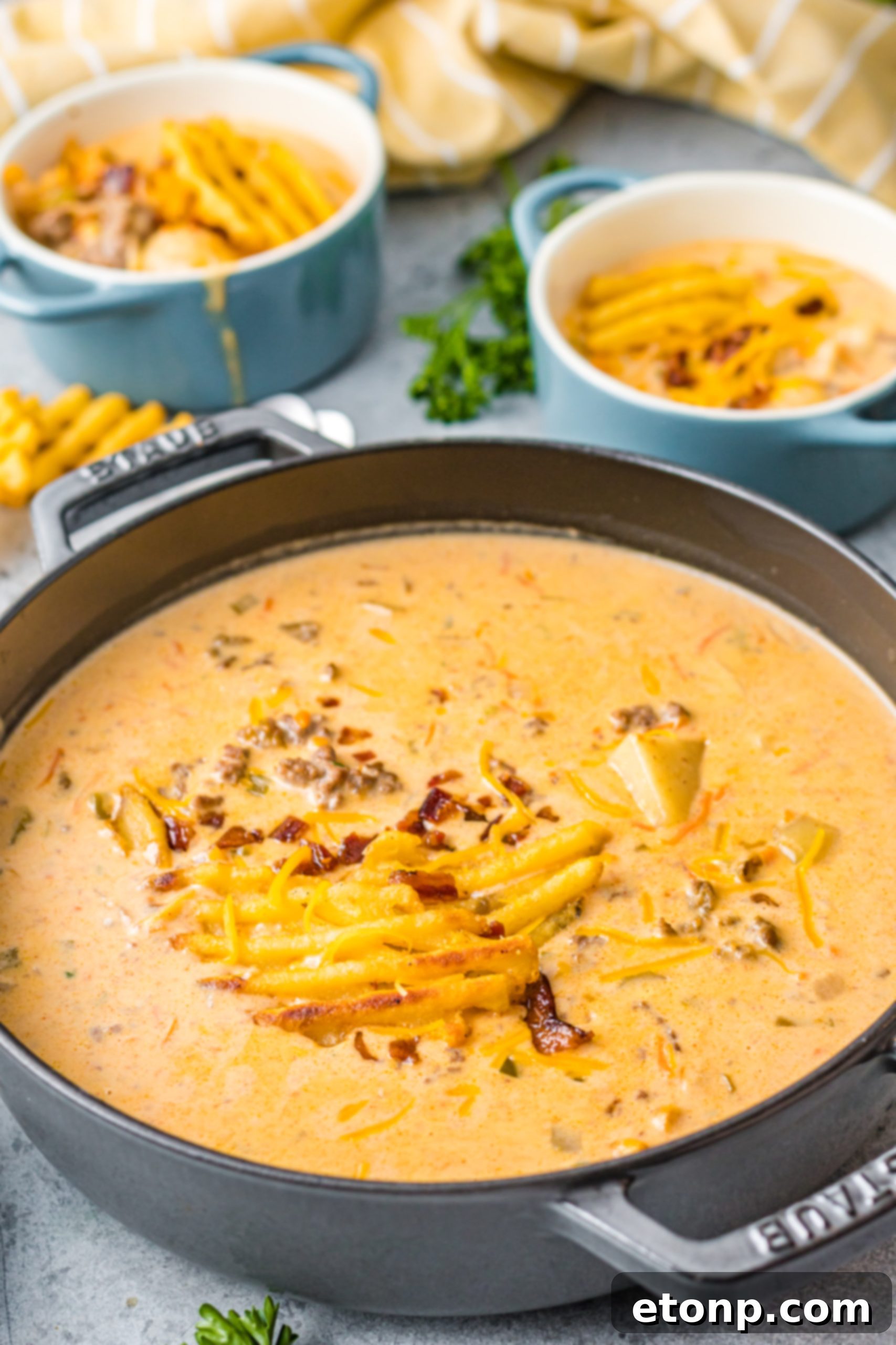 A close-up shot of the finished slow cooker cheeseburger soup, showing its rich, thick texture and toppings.