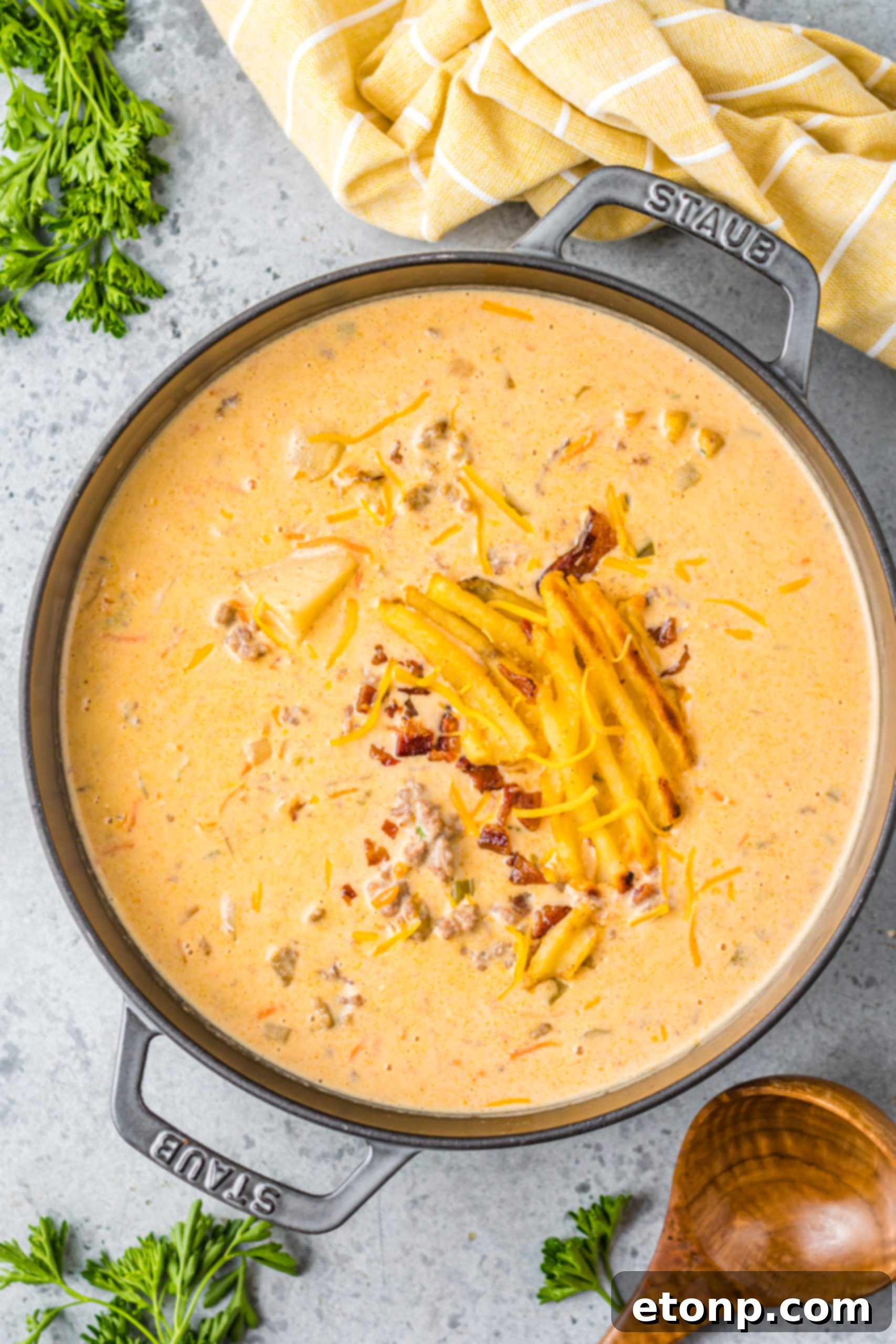 A bowl of slow cooker cheeseburger soup with a topping of shredded cheese and fresh herbs, ready to be served.