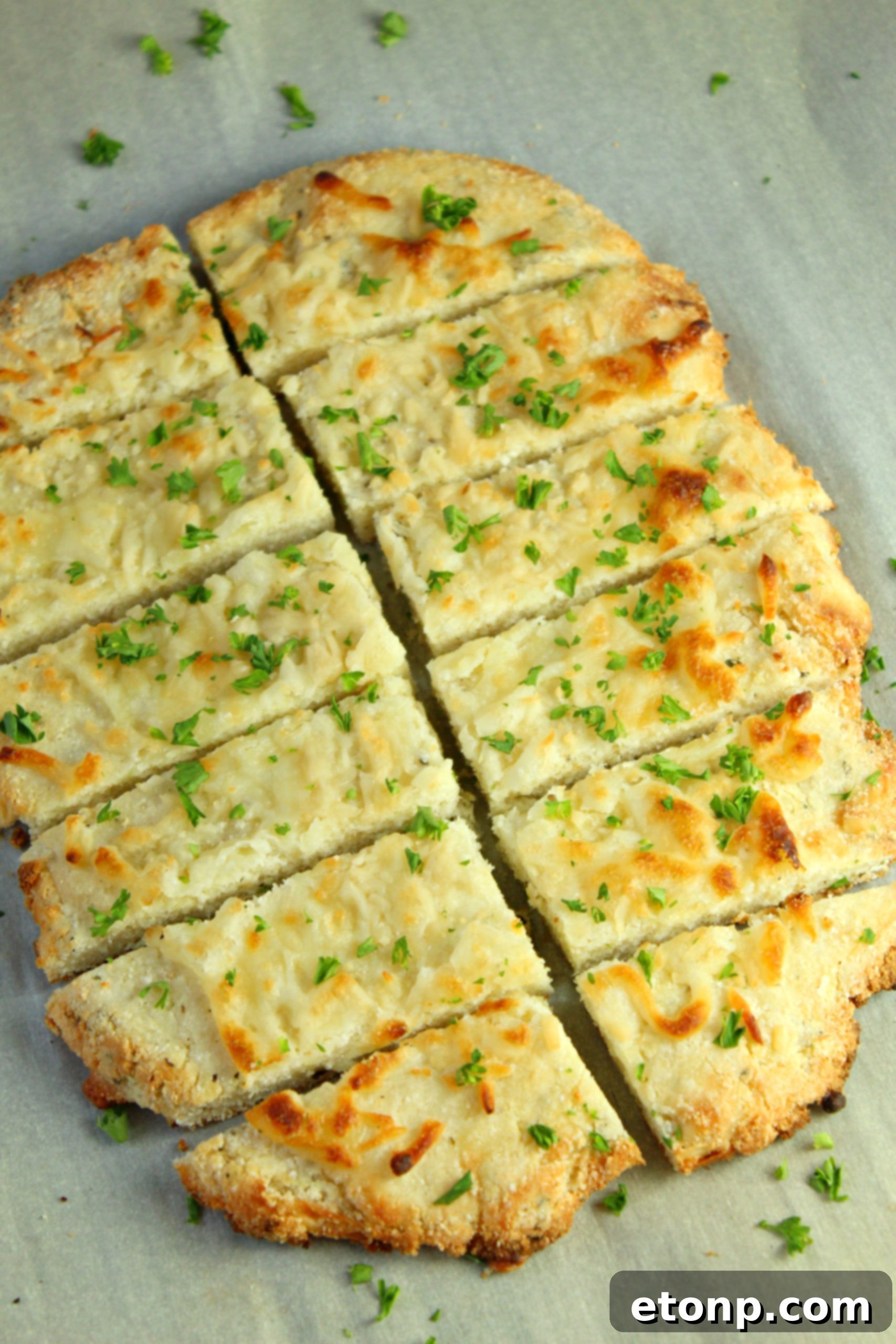 Four Cheese Keto Breadsticks Deliciously Low Carb 7 A batch of Four Cheese Keto Breadsticks artfully arranged on a wooden cutting board with a side of dipping sauce.
