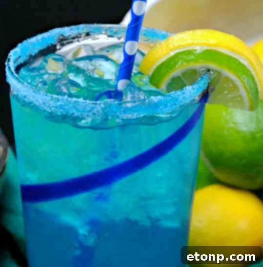 Electric Lemonade Garnish Detail An Electric Lemonade drink with a festive blue sugar rim and a fresh lemon slice, emphasizing the drink's presentation.