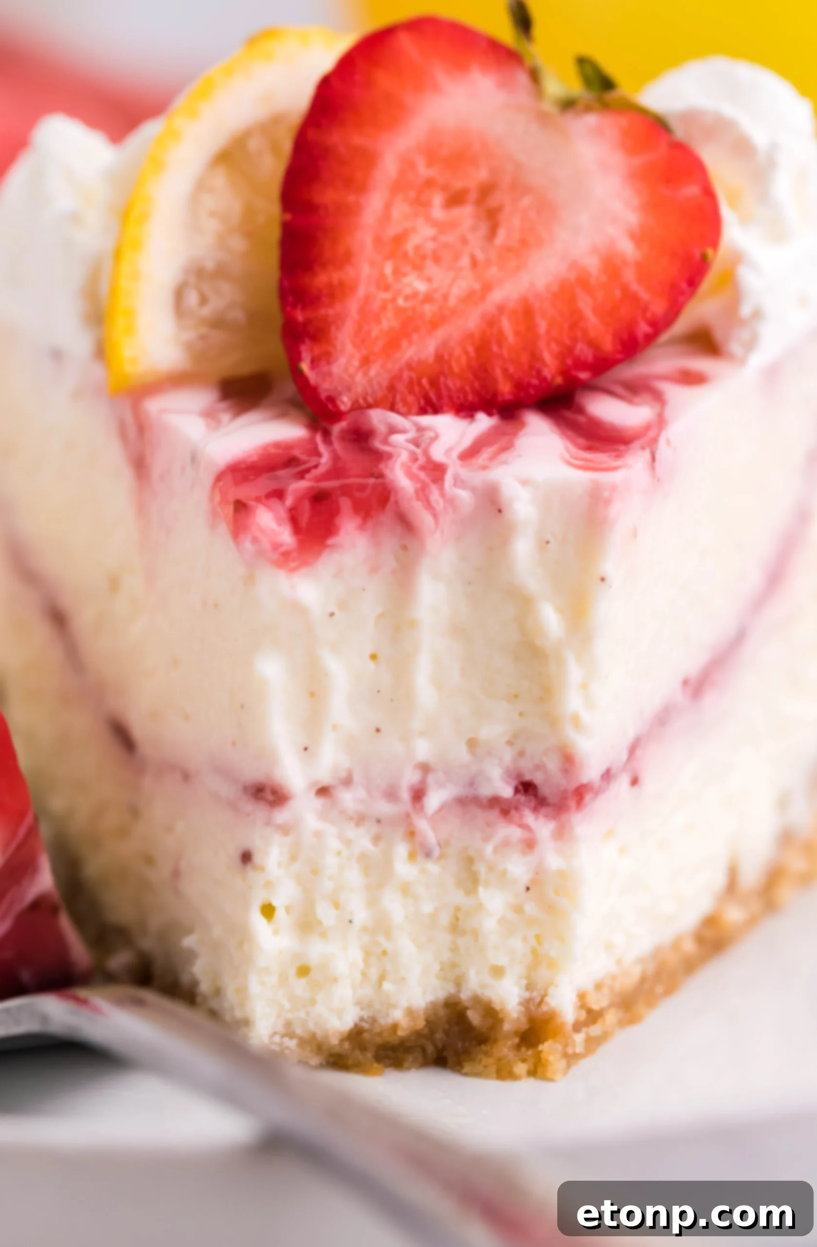 A stunning full view of the Strawberry Lemon RumChata Cheesecake, elegantly decorated with fluffy whipped cream, fresh strawberries, and vibrant lemon slices.