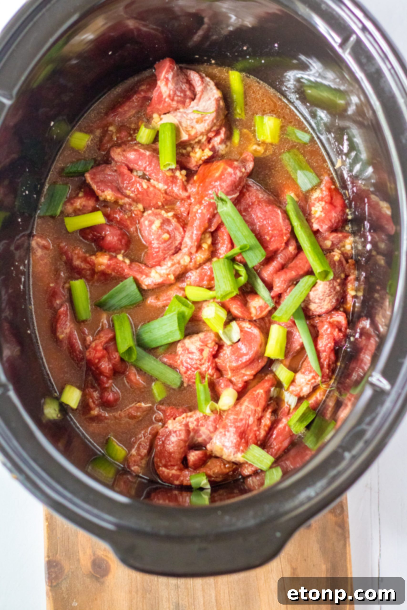 Slow Cooker Mongolian Beef in a white bowl with chopsticks