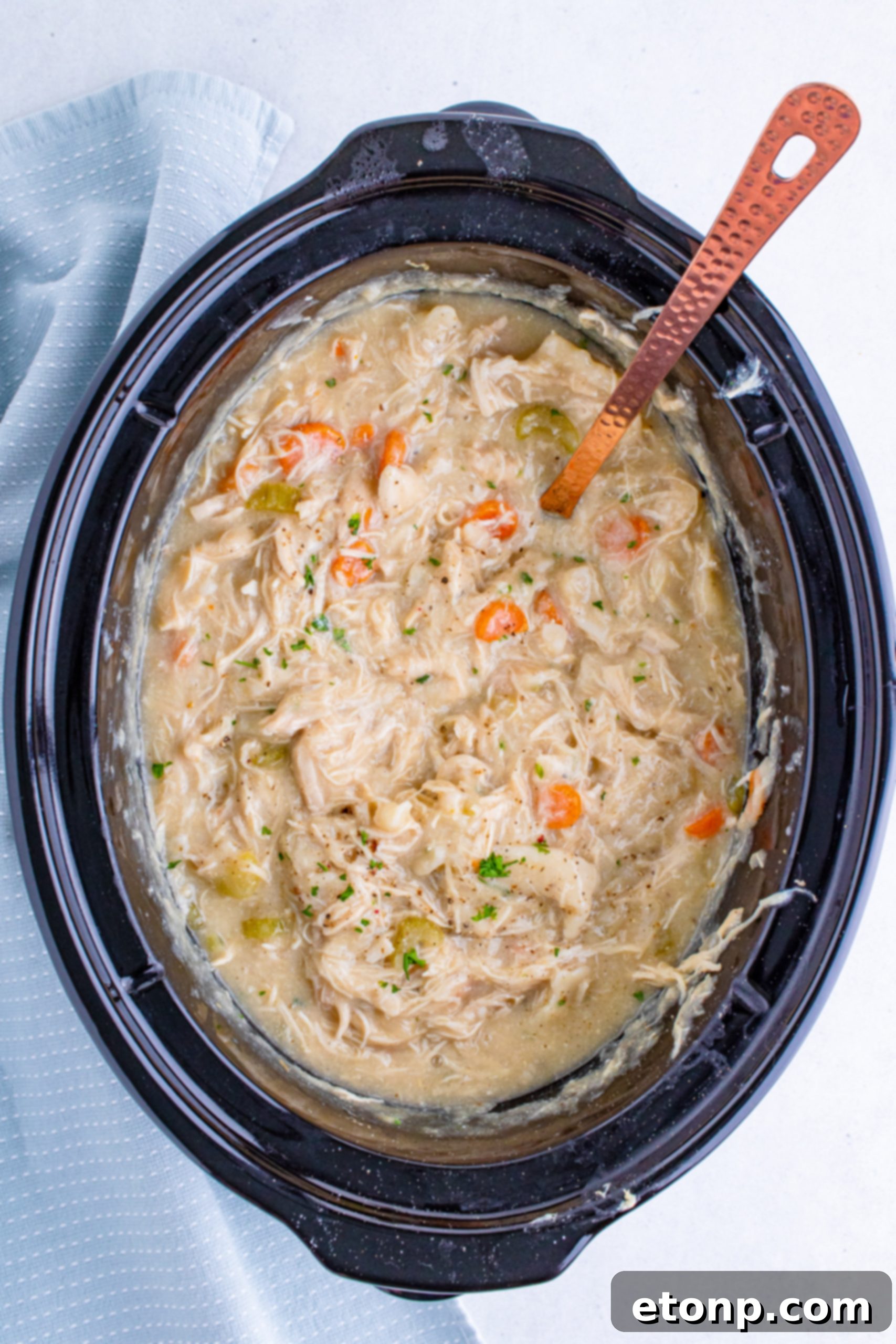 Two forks shredding cooked chicken breast in a bowl, a common step for preparing shredded chicken in recipes.