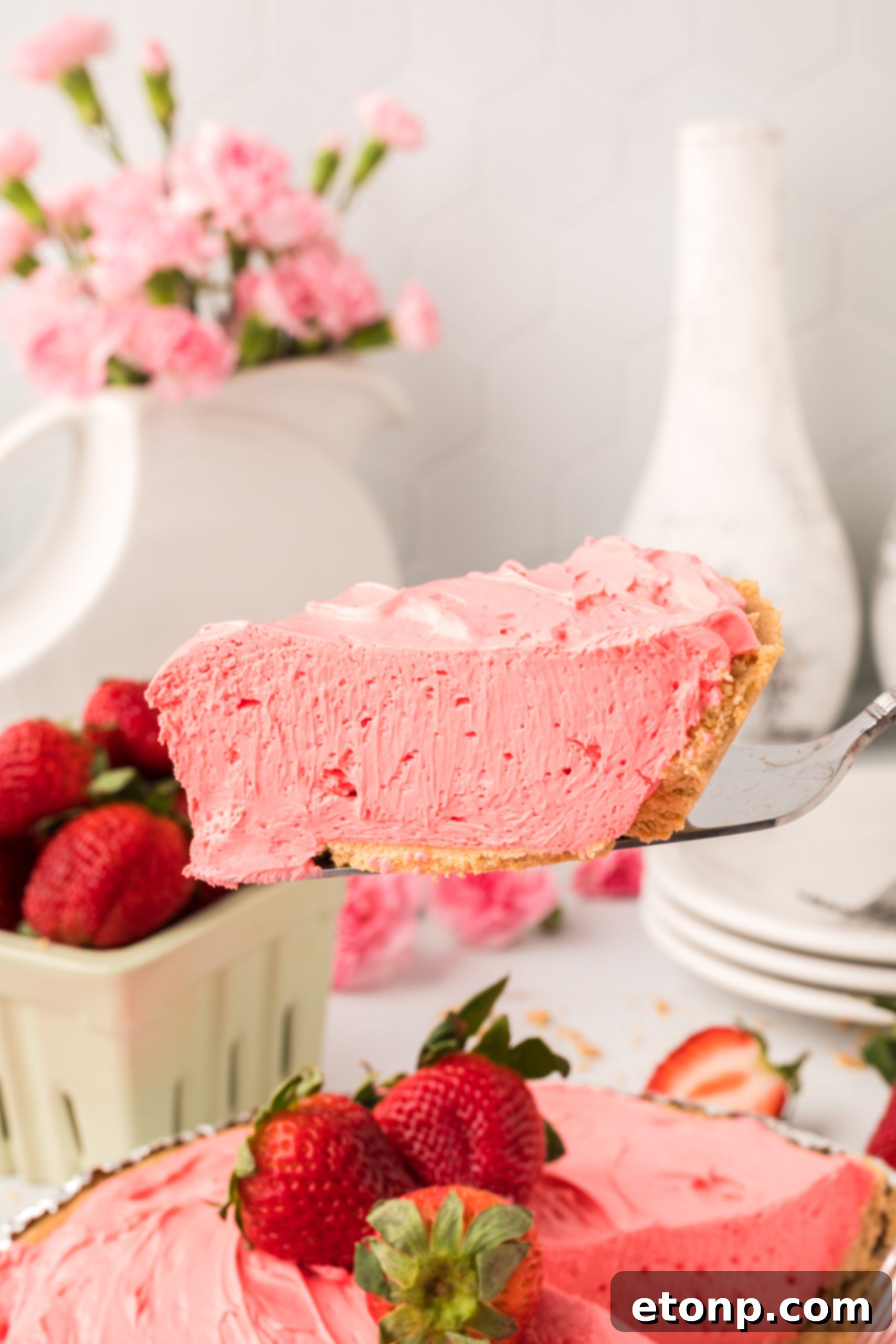 A close-up shot of a single serving of Strawberry Kool-Aid pie, generously topped with whipped cream and fresh strawberry slices, highlighting its appealing presentation.