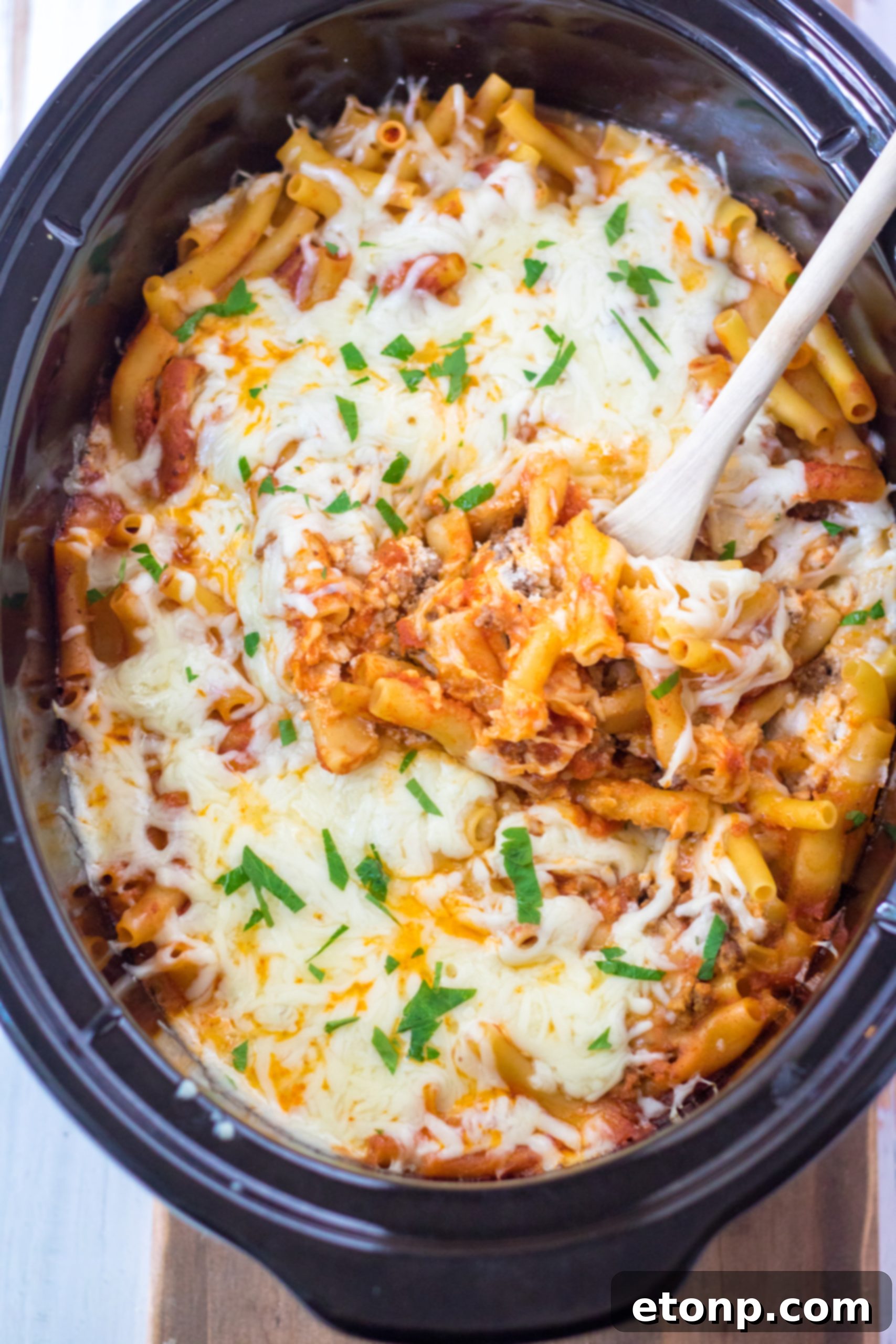 Close-up of Slow Cooker Cheesy Baked Pasta in a crock pot, ready to be served, showing melted cheese and rich sauce.