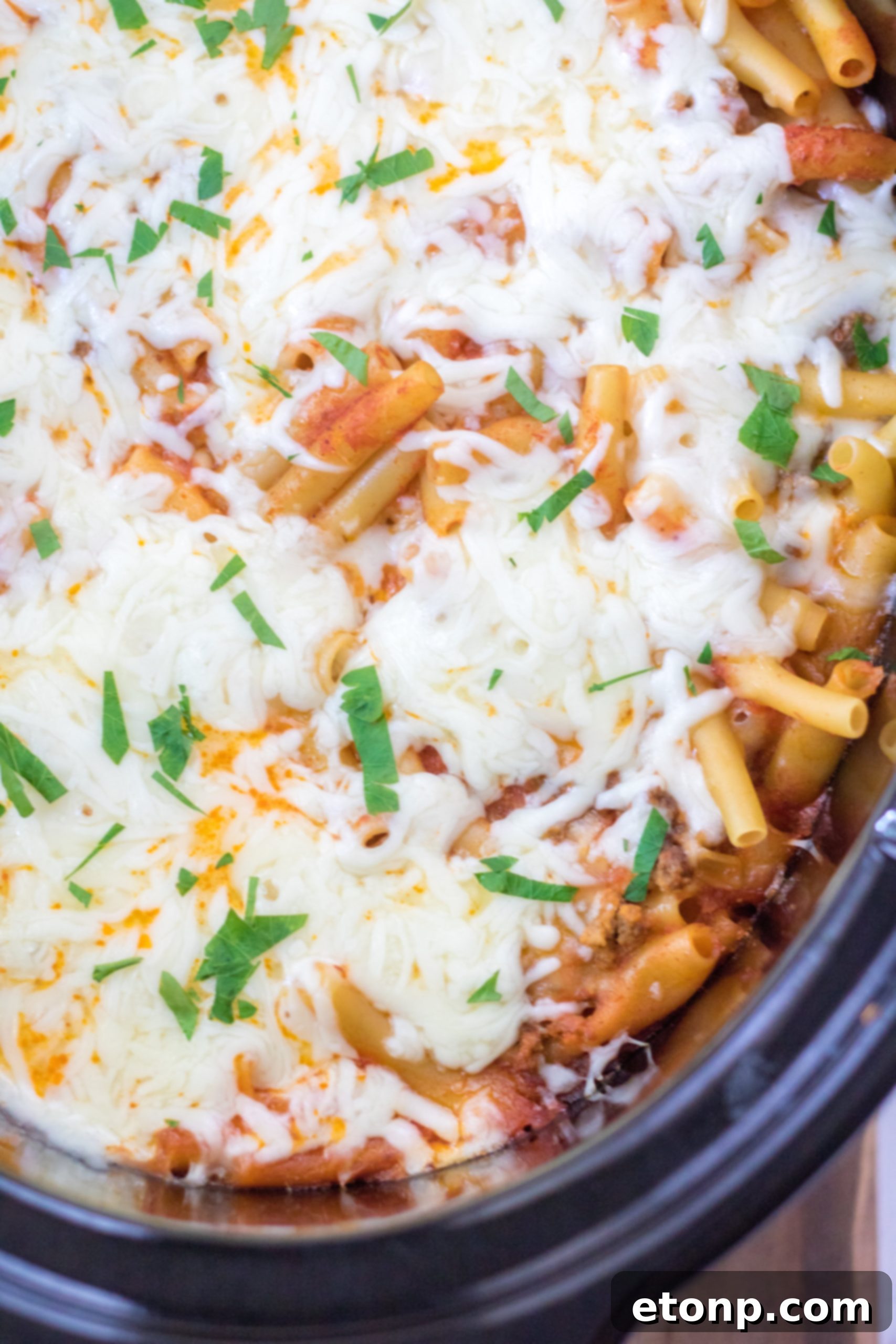 Another enticing close-up of the Slow Cooker Cheesy Baked Pasta, highlighting the melted mozzarella and rich tomato sauce.