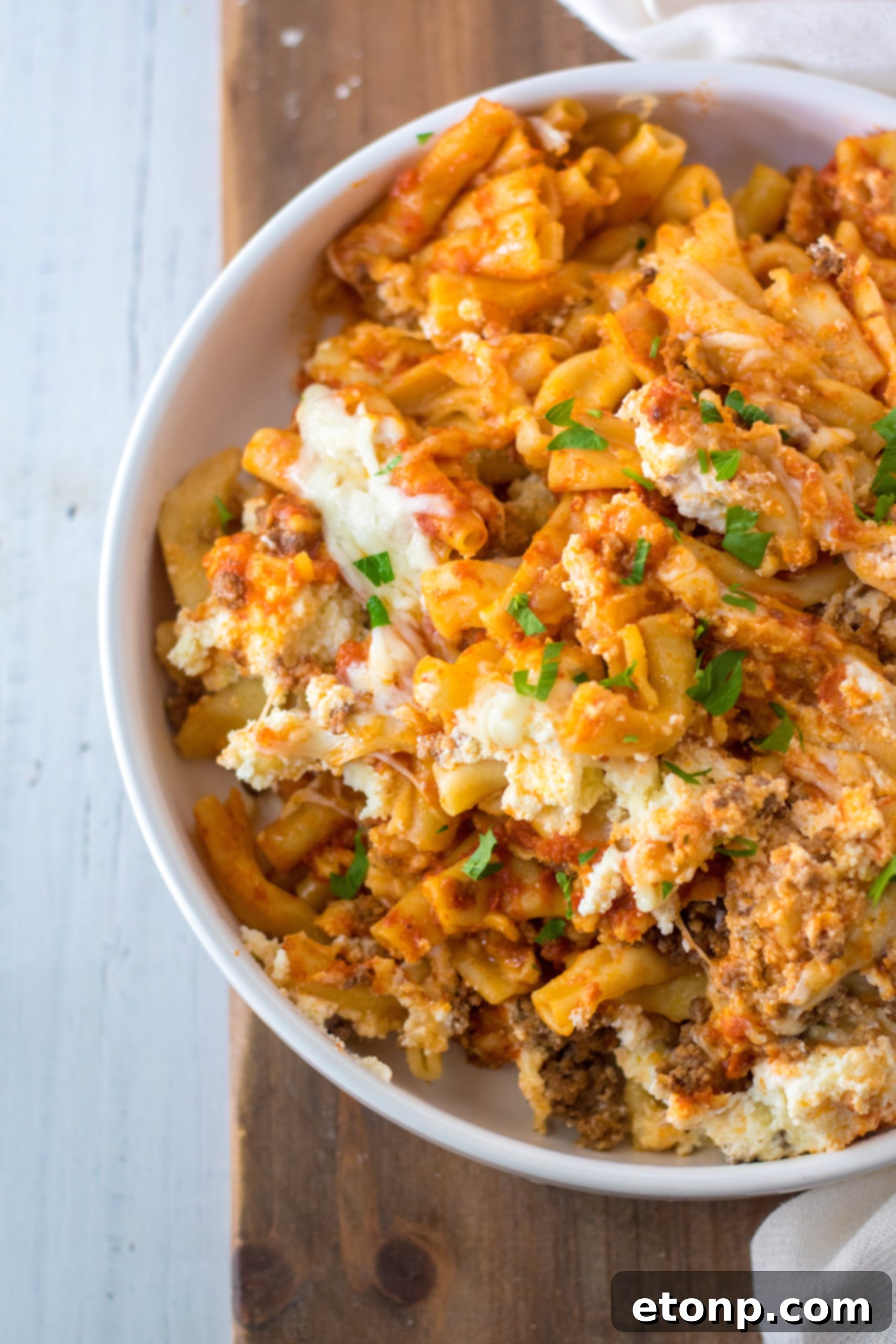Ingredients for Slow Cooker Cheesy Baked Pasta laid out, including ground beef, pasta, sauces, and cheeses.
