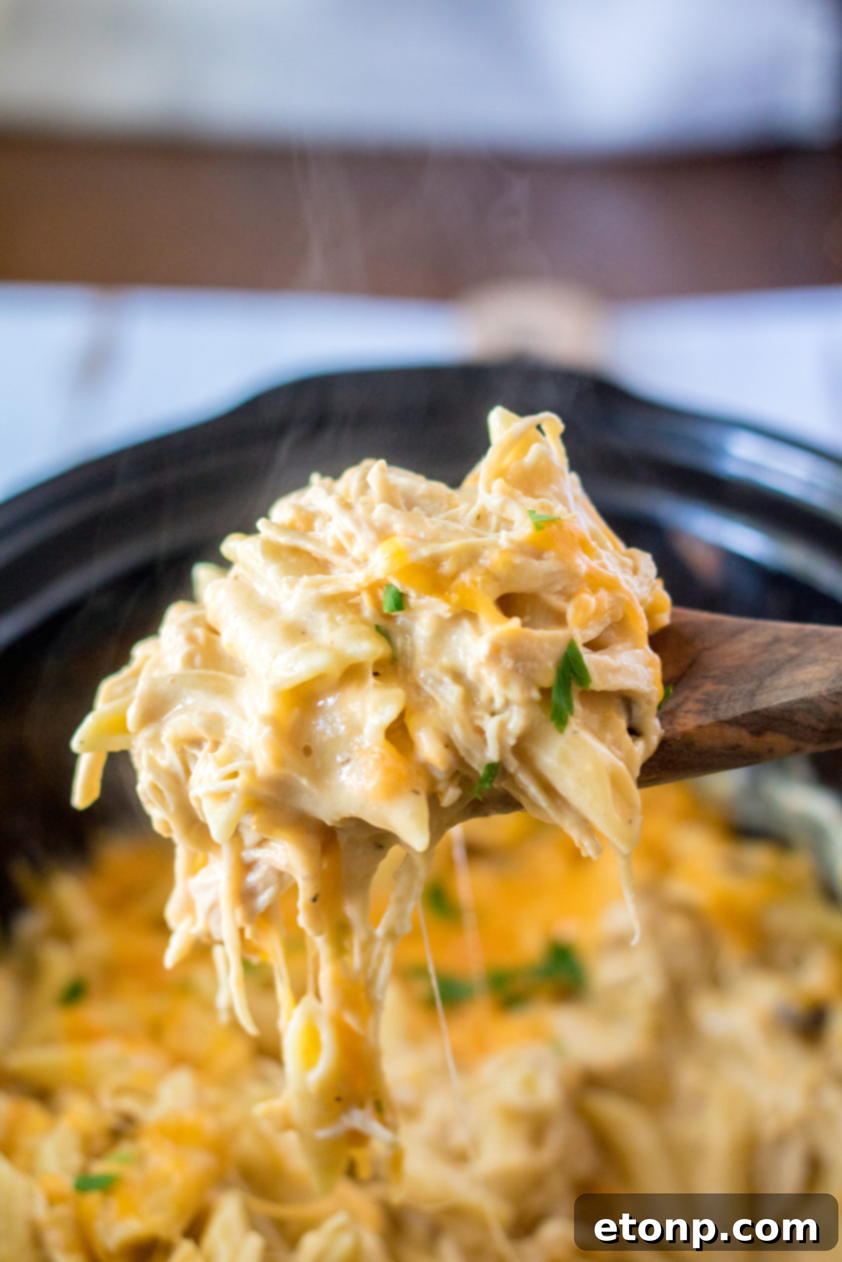 A serving of Slow Cooker Cheesy Chicken Penne in a bowl, with a fork, ready to eat