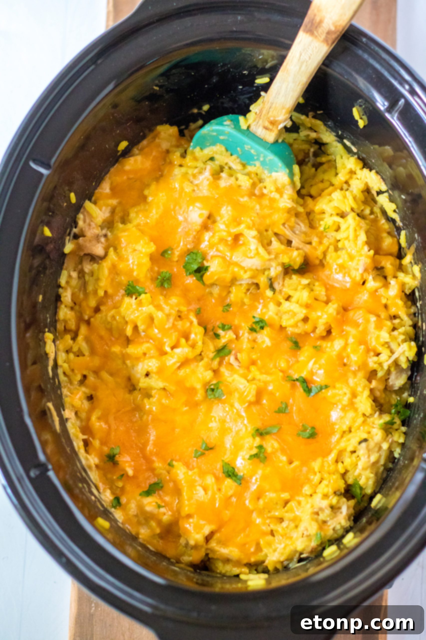 Sour cream and Velveeta cheese being stirred into the slow cooker chicken mixture.