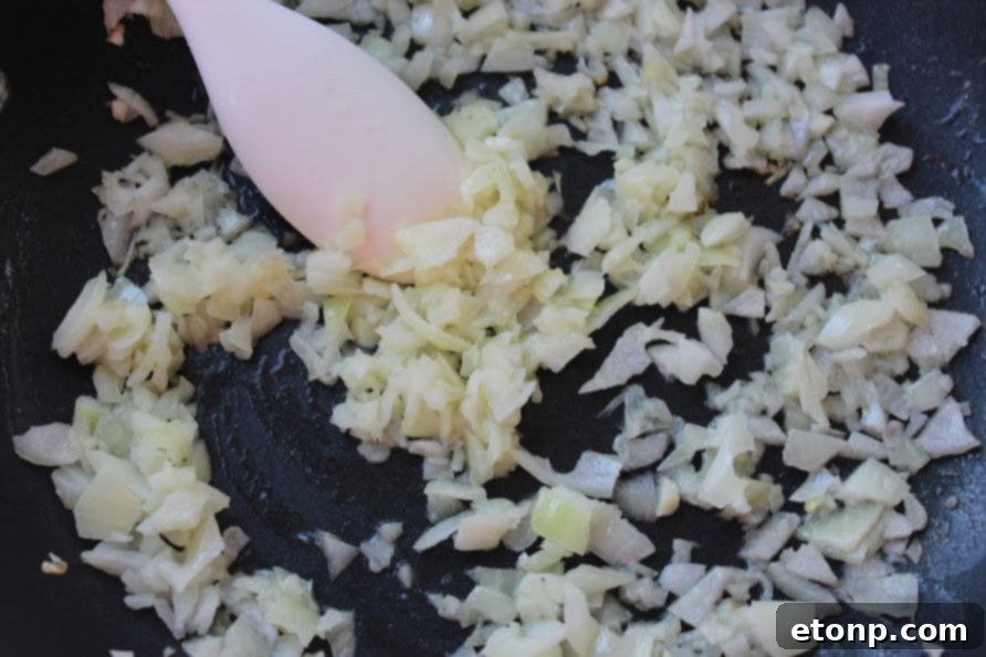 Chopped chicken and vegetables being stir-fried in a large pan for fried rice.