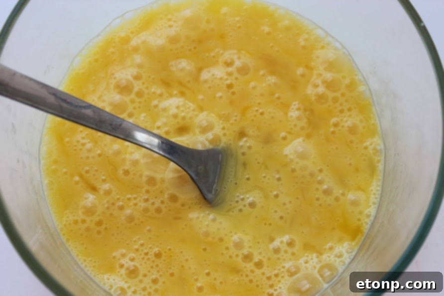 Mixing cooked eggs and vegetables into rice in a large skillet.