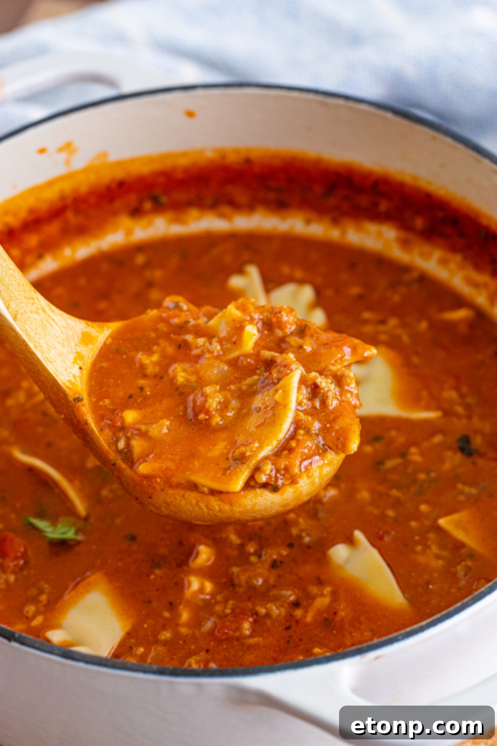 Close-up of a spoon scooping Lasagna Soup with noodles, meat, and cheese.