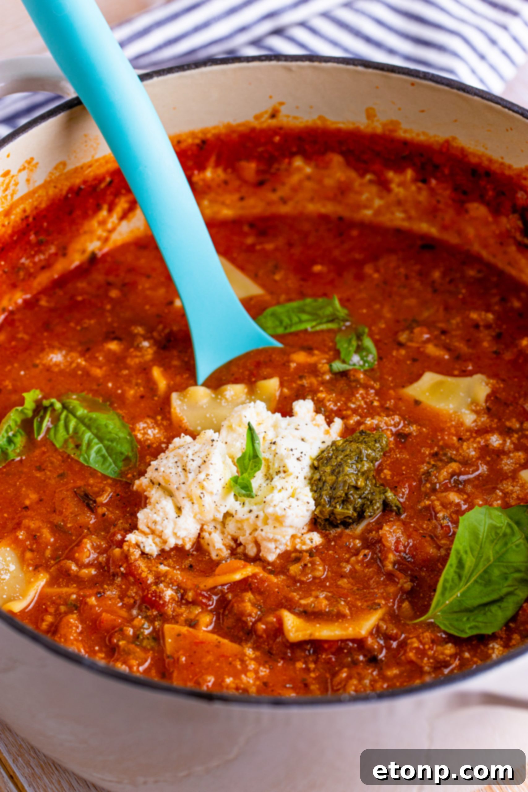 A bowl of Lasagna Soup, garnished with a generous dollop of ricotta cheese mixture.