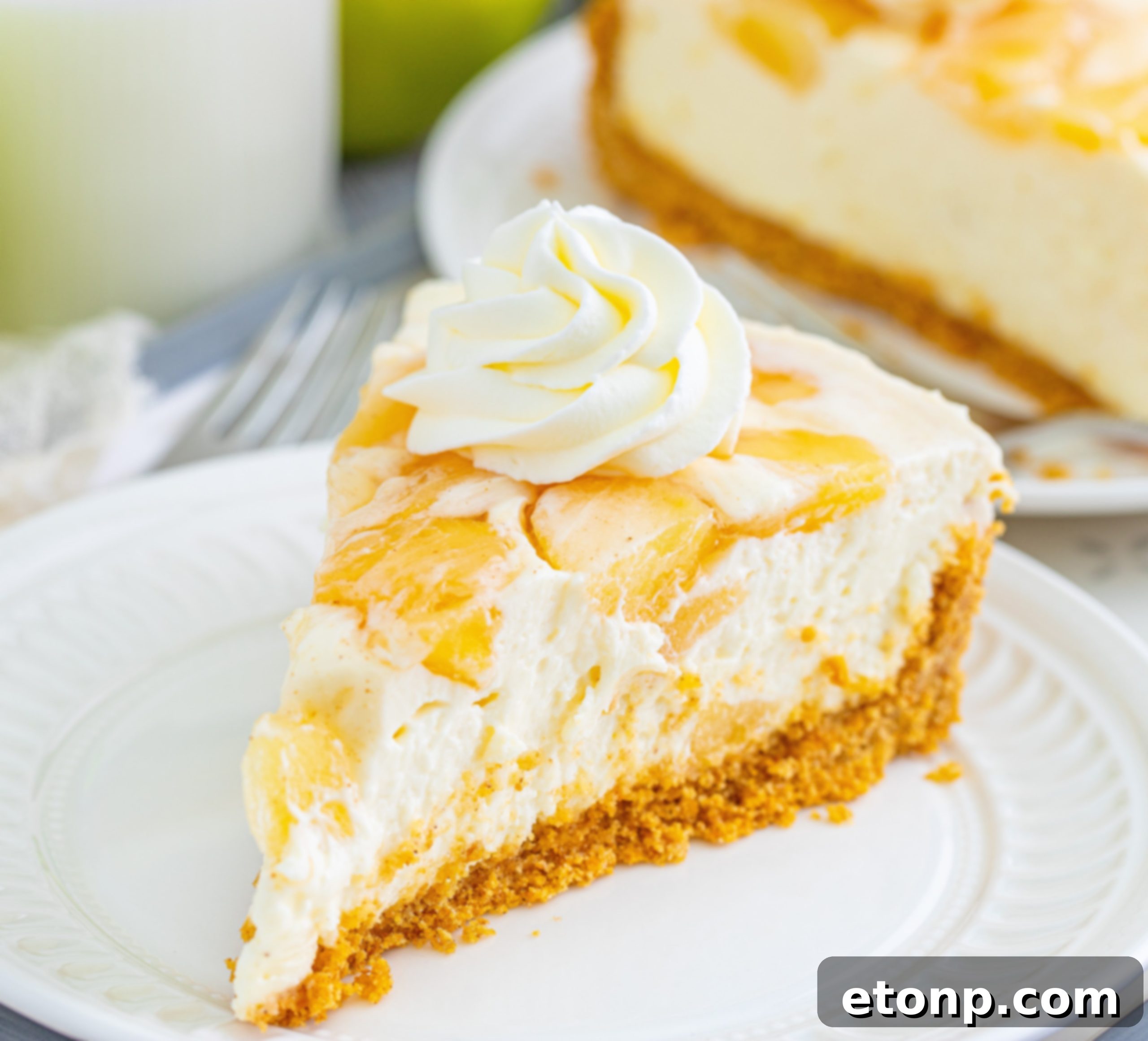 A whole No Bake Apple Cheesecake, beautifully presented on a cake stand, ready for slicing.