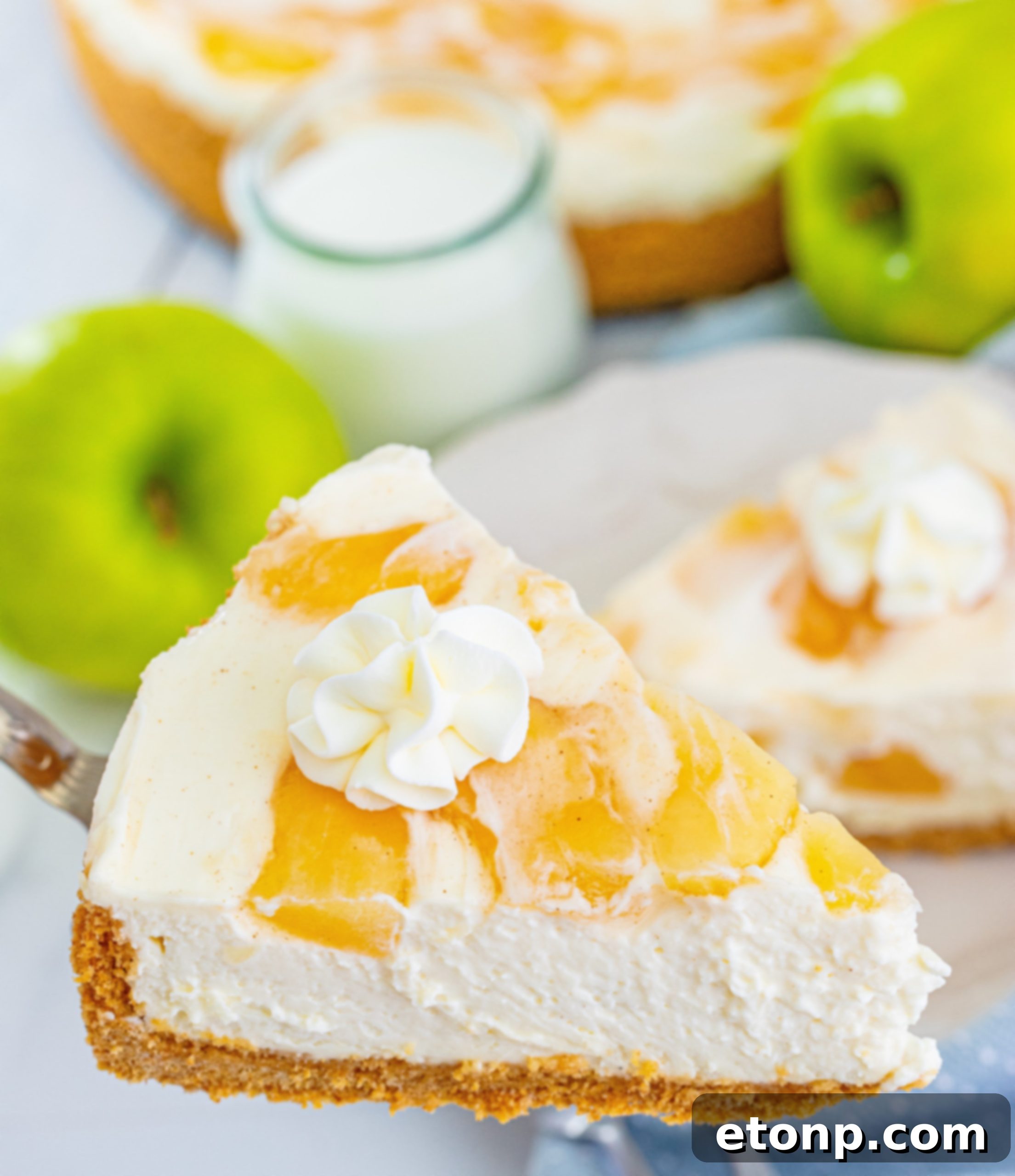 A slice of No Bake Apple Cheesecake on a plate, showing the distinct layers and rich apple topping.