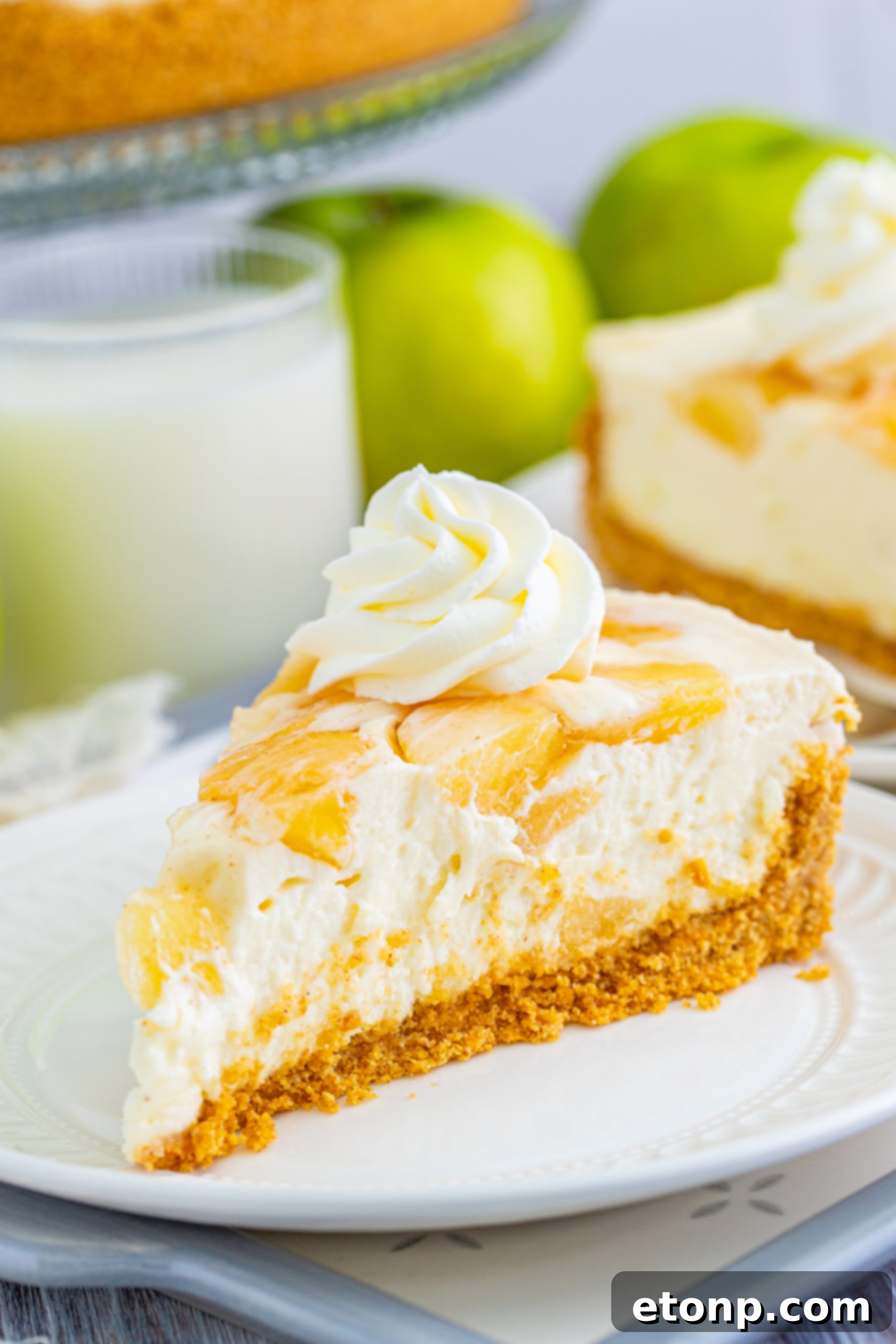 A side view of a No Bake Apple Cheesecake, showing the layers of crust, creamy filling, and apple topping.